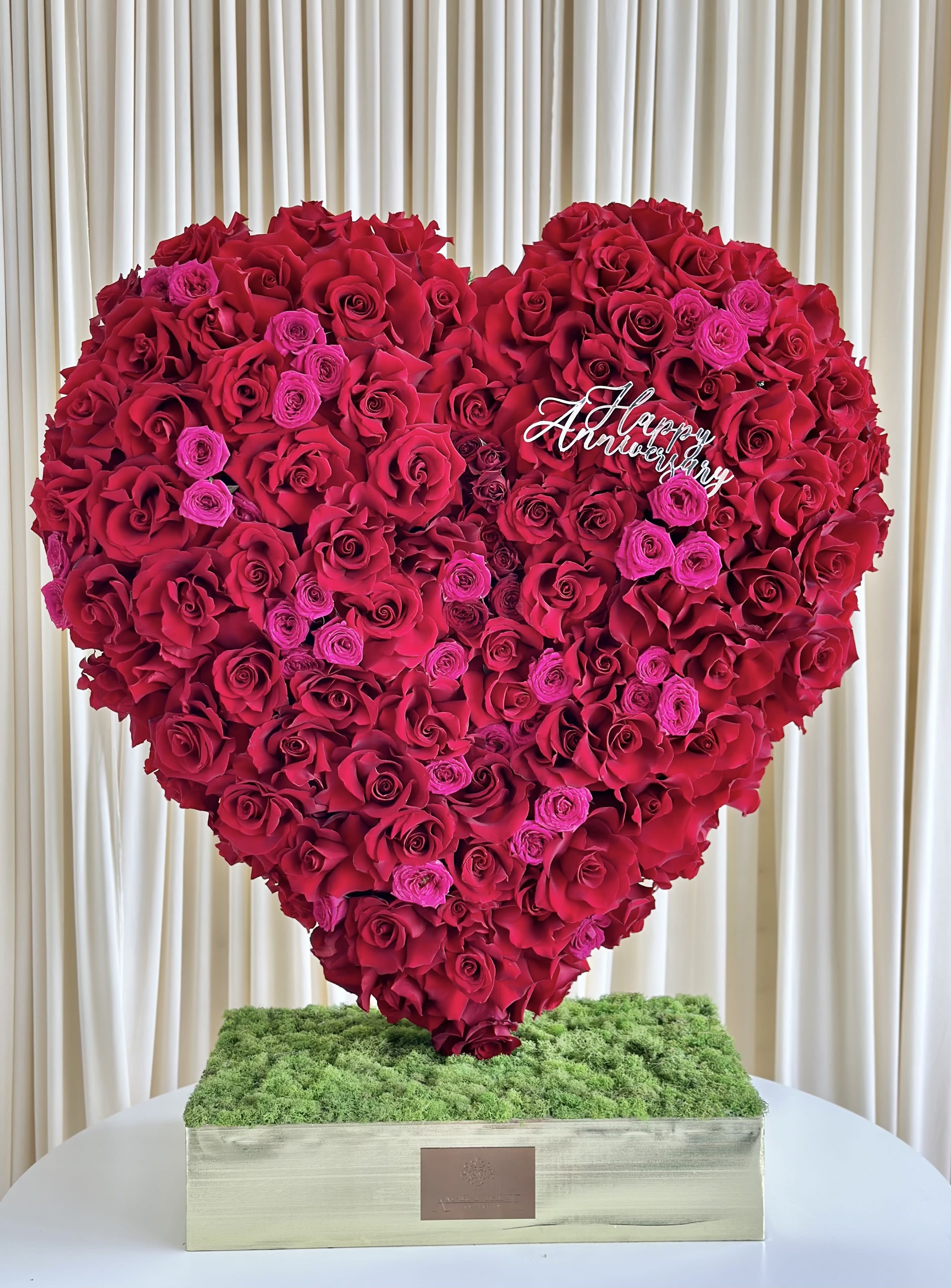 Romantic Radiance - !!! Happy Anniversary not included!!! Ignite the flames of love with our &quot;Romantic Radiance&quot; Heart-Shaped Anniversary Arrangement. Crafted with care, this captivating arrangement features a lavish display of red and fuchsia roses, delicately arranged to form a heart shape, symbolizing your boundless love and affection. Adorned with a gleaming &quot;Happy Anniversary&quot; in gold, this arrangement becomes an expression of your everlasting commitment and joyous journey together. Celebrate your special day with the romantic allure of &quot;Romantic Radiance&quot; and cherish the memories forever. 