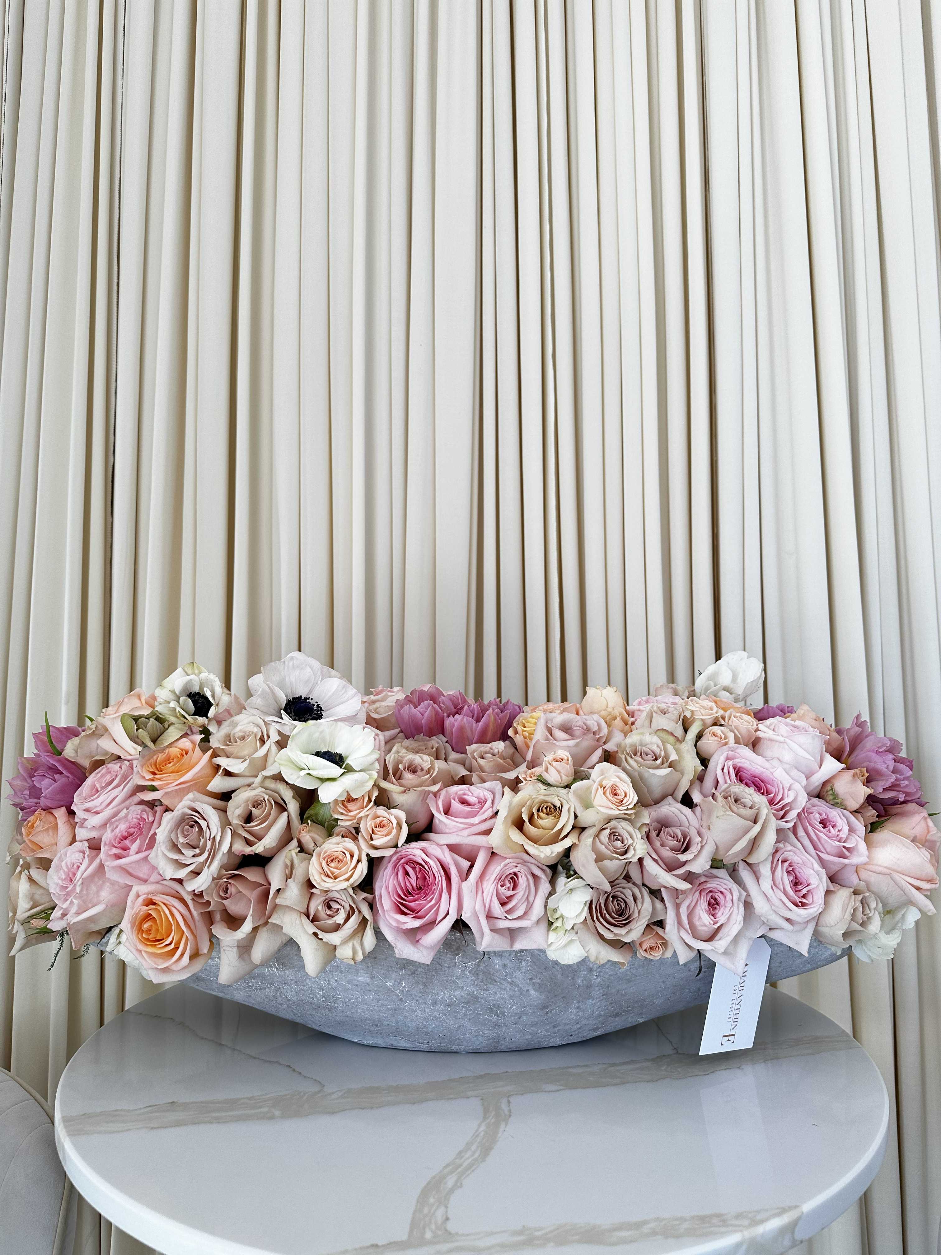 Textured Tapestry - Woven together like a rich tapestry, this captivating bouquet features a beautiful blend of tulips, roses, garden roses, and anemones. Each bloom offers a unique texture and vibrancy, while the unexpected concrete vase adds a touch of modern flair. This stunning arrangement is sure to be a conversation starter.