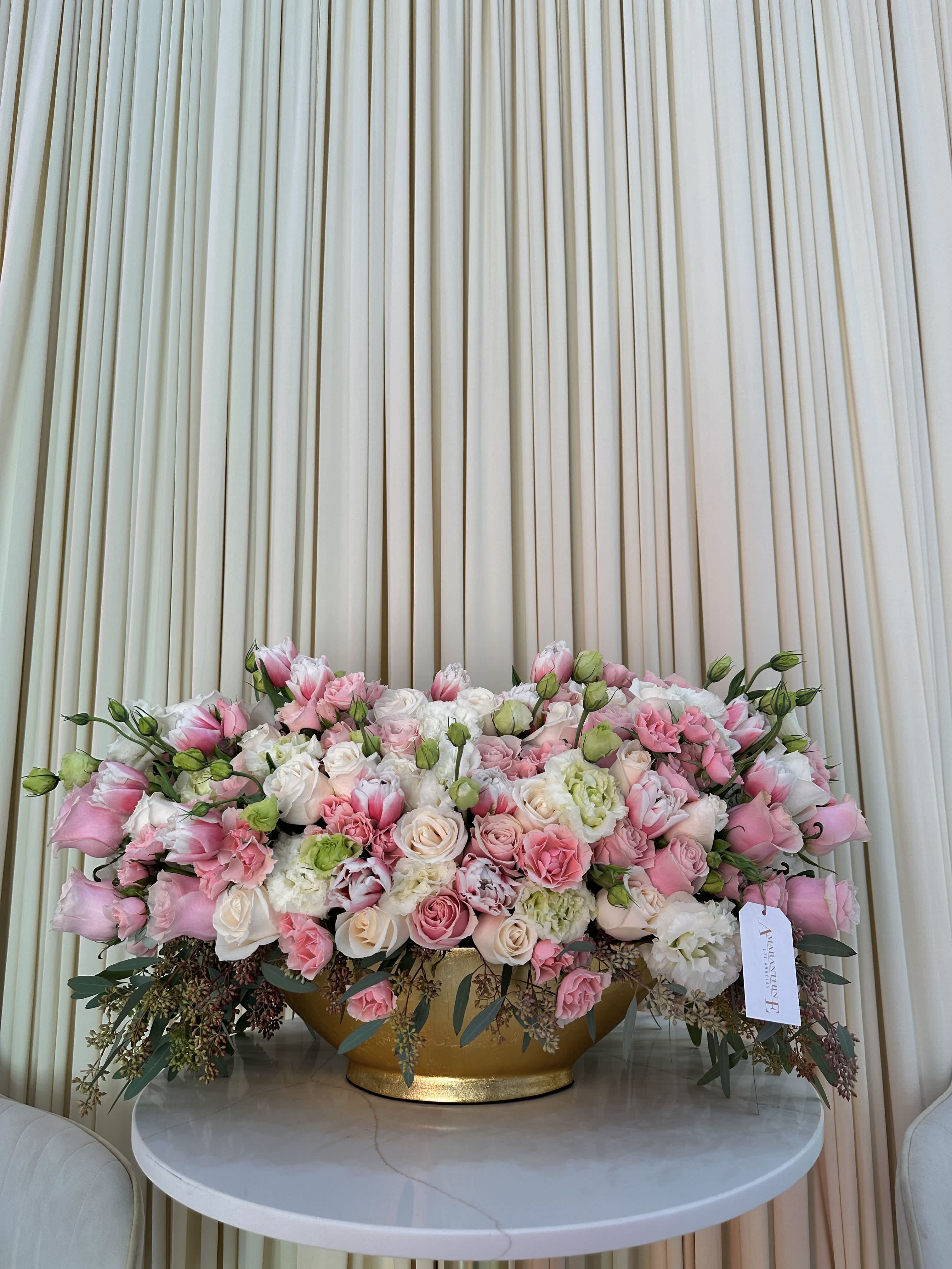 Blooming Celebration - This stunning bouquet features a vibrant mix of pink and white roses, pink baby roses, pink tulips, green Lisianthus, and hydrangea, all showcased in a beautiful gold vase. The soft pink and white blooms are perfectly complemented by the lush greenery, creating a breathtaking display. The gold vase adds a touch of glamour and makes this a luxurious gift for any occasion.  