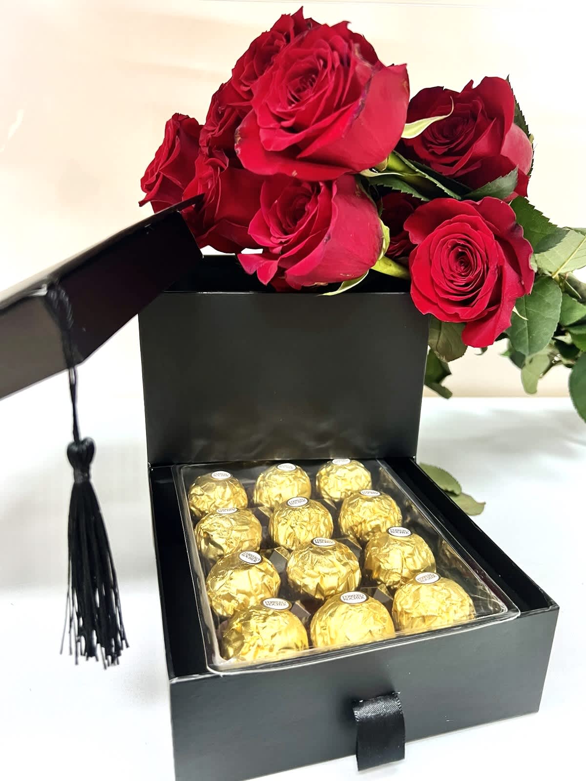 Graduation- A dozen roses & chocolates beautifully arranged into a Grad Hat box. Graduation- A dozen roses & chocolates beautifully arranged into a Grad Hat box. - 12 Roses in a hat. One color. 1 pack Ferrero Rocher- 12 pieces Square Graduation Hat Box with drawer specifics- * Material: Cardboard, Fine Paper. Recyclable. * Size of the box : 16.5 cm x 16.5 cm x 16.5 cm / (6.5″ x 6.5″ x 6.5″ inch). * Size of the lid : 17.8 cm x 17.8 cm / (7″x 7″ inch) * Size of the drawer : 16.5 cm x 5.25 cm x 6.35 cm / (6.5″ x 6″ x 2.5″ inch) * Please allow 1-2 cm errors due to manual measurement