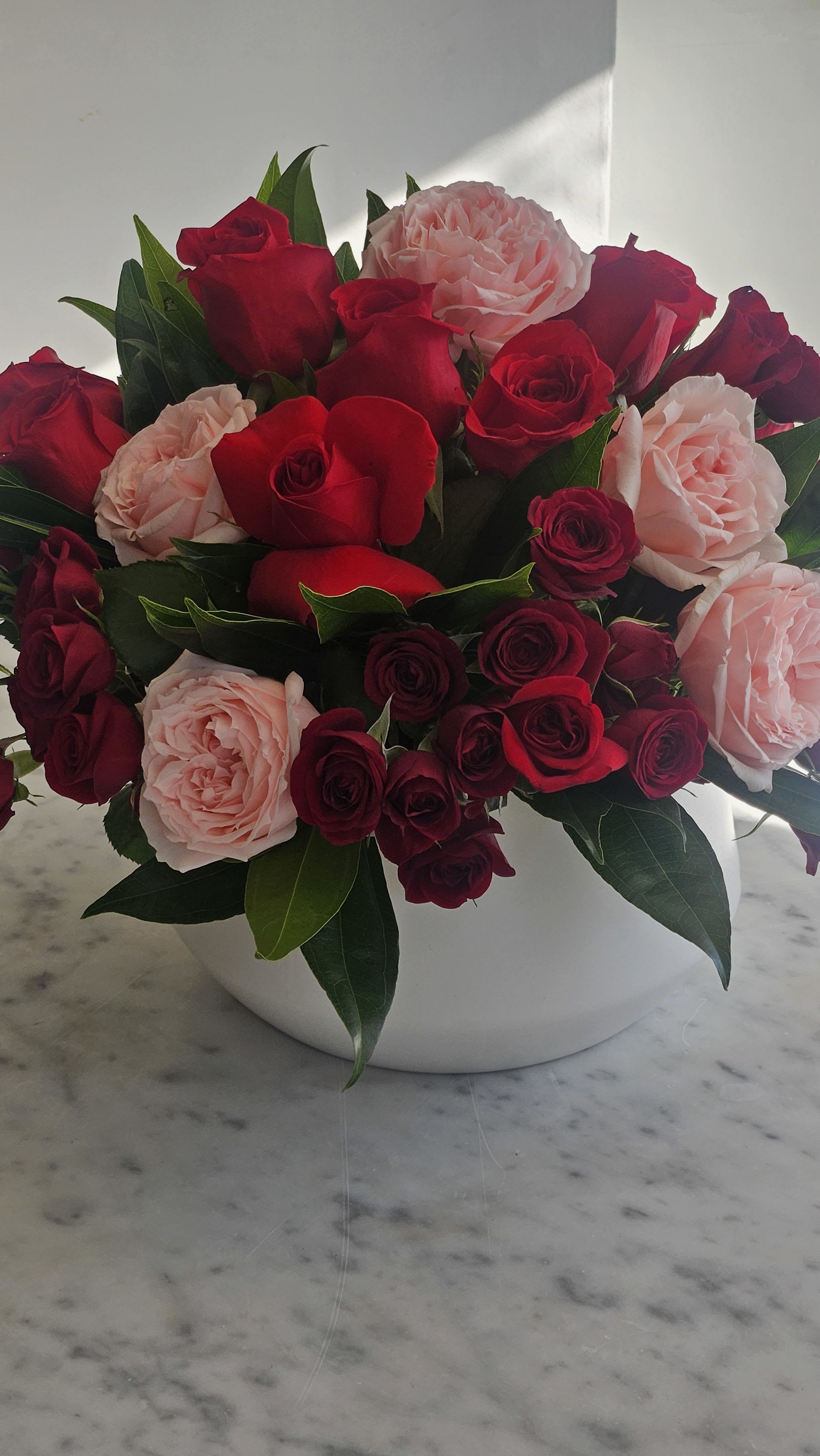 Exquisite  - A stunning vase arrangement that includes a Dozen red roses, pink garden roses and red spray roses mixed with a beautiful assortment of soft greenery.