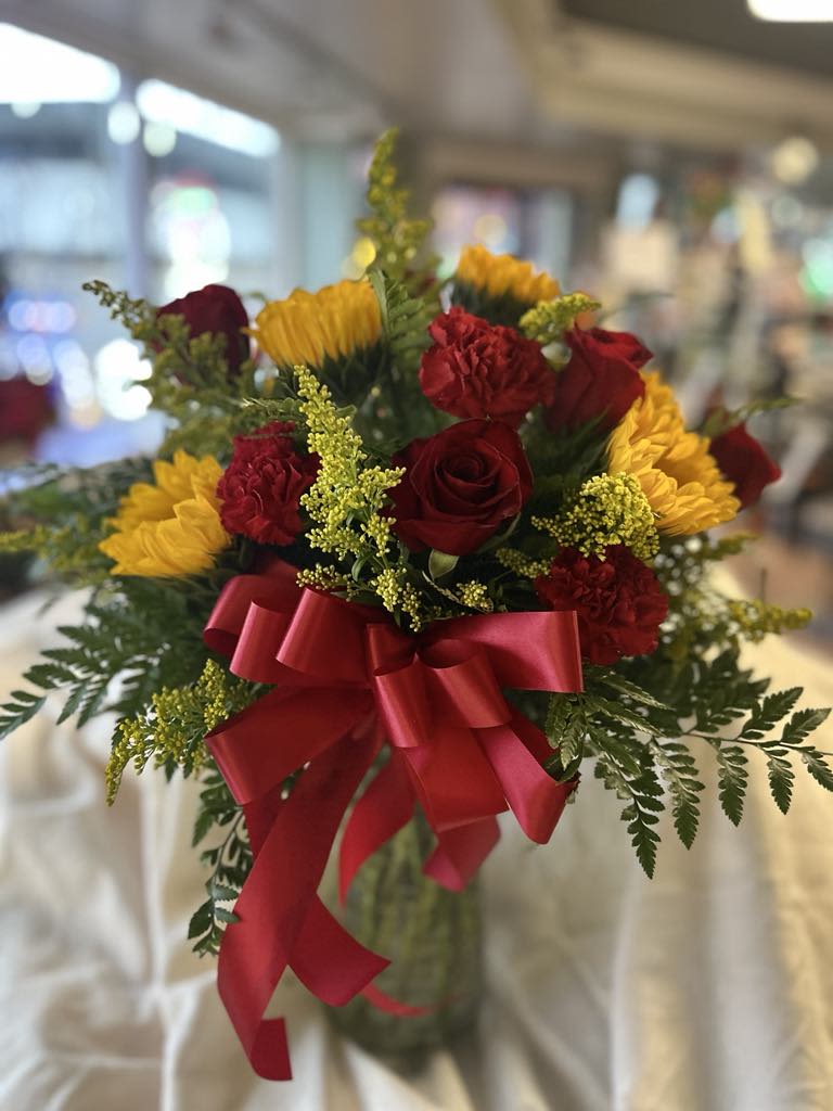 XOXO - Vibrant composition of sunflowers, carnations, and roses. A method to demonstrate your affection for that special person in a delightful and unique manner.