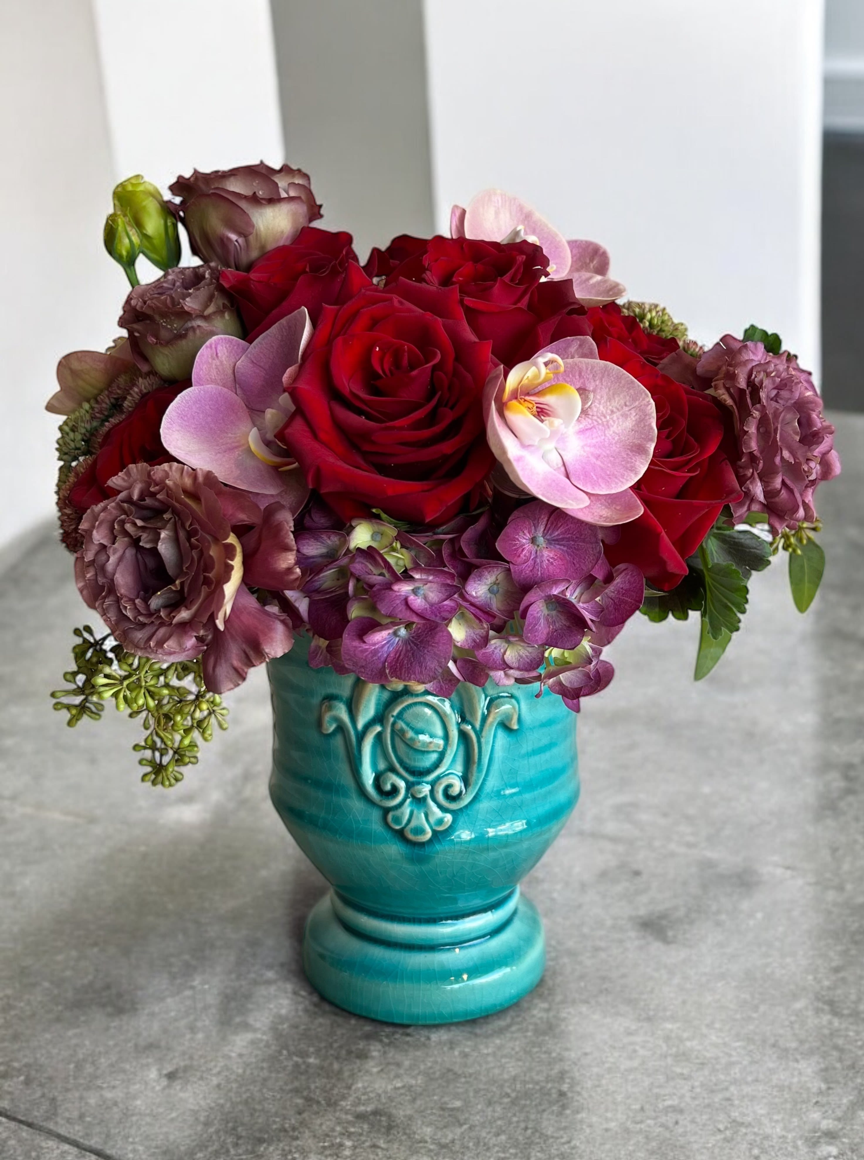Turquoise and Roses  - 1 Dozen short red roses with orchid accents in a beautiful turquoise keepsake vessel.