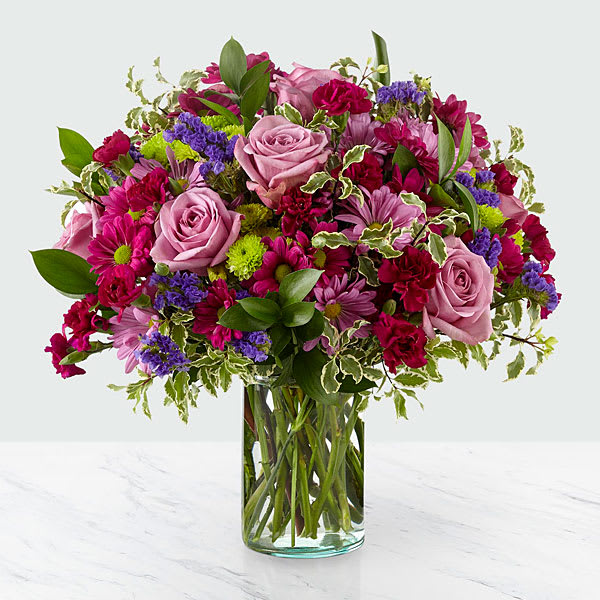 The FTD Sweet Nothings Bouquet - Dazzle your customers with stunning violet and green hues set within a glass cylinder vase. A collection of roses daisies and statice our Sweet Nothings Bouquet sends sweet sentiment deep within each bloom. GOOD bouquet is approx. 14″H x 14″W. BETTER bouquet is approx. 15″H x 15″W. BEST bouquet is approx. 16″H x 17″W.