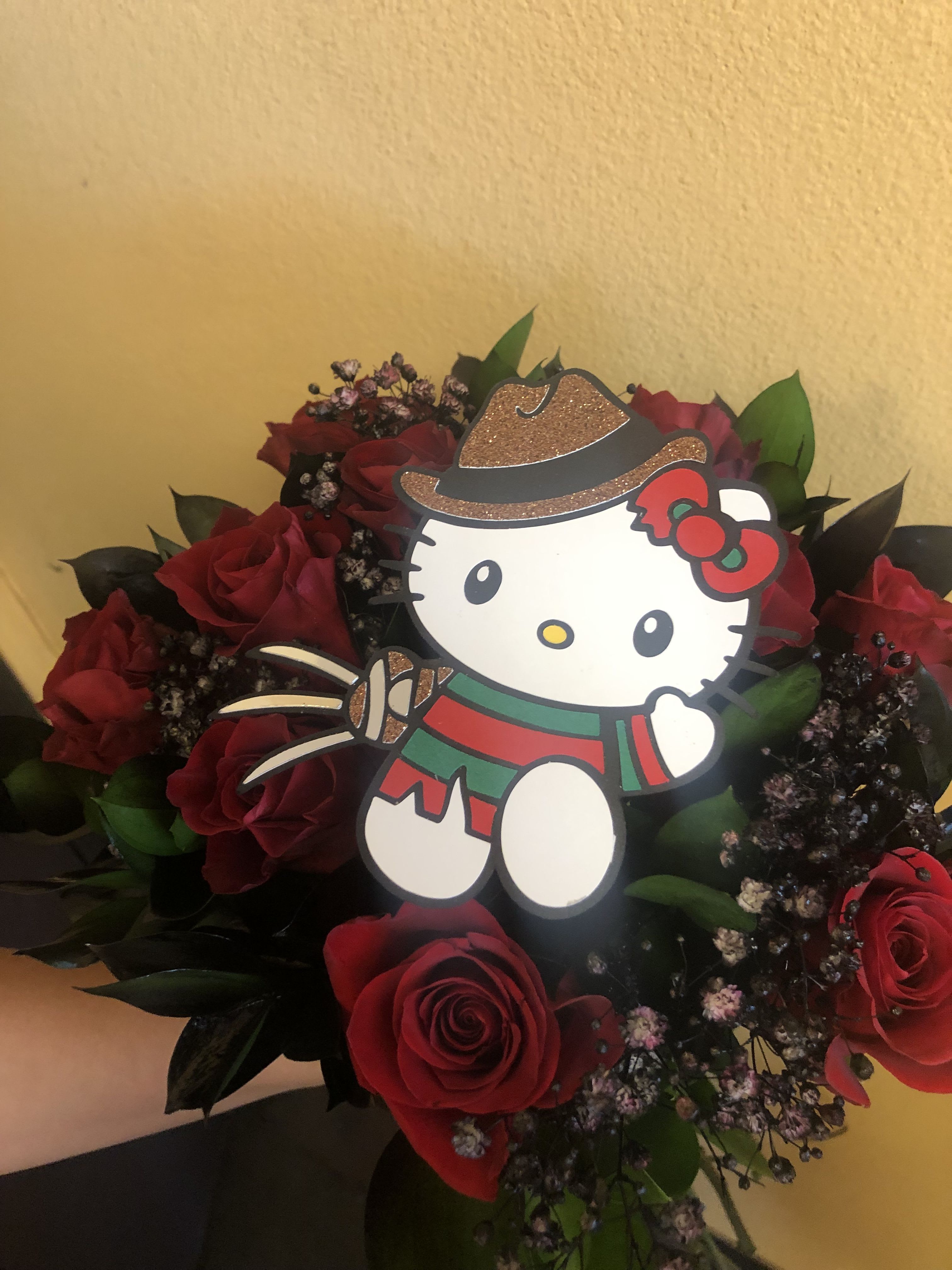 HALLOWEEN WRAP (HELLO KITTY DRESSED AS FREDDIE KRUEGER) - 12 RED ROSES WITH SPRAY PAINTED BABY BREATH AND RUSCUS IN BLACK.  WITH THE PAPER CUT OFF OF HELLO KITTY DRESSES AS FREDDIE KRUGER (THE CUT OFF IS ABOUT 5 INCHES TALL )THIS IS A WRAP NO VASE INCLUDED.  WE WRAP IT IN KOREAN BLACK PAPER  STANDER PRICE IS 12 ROSES DELUXE PRICE IS 18 ROSES PREMIUM PRICE IS 24 ROSES 