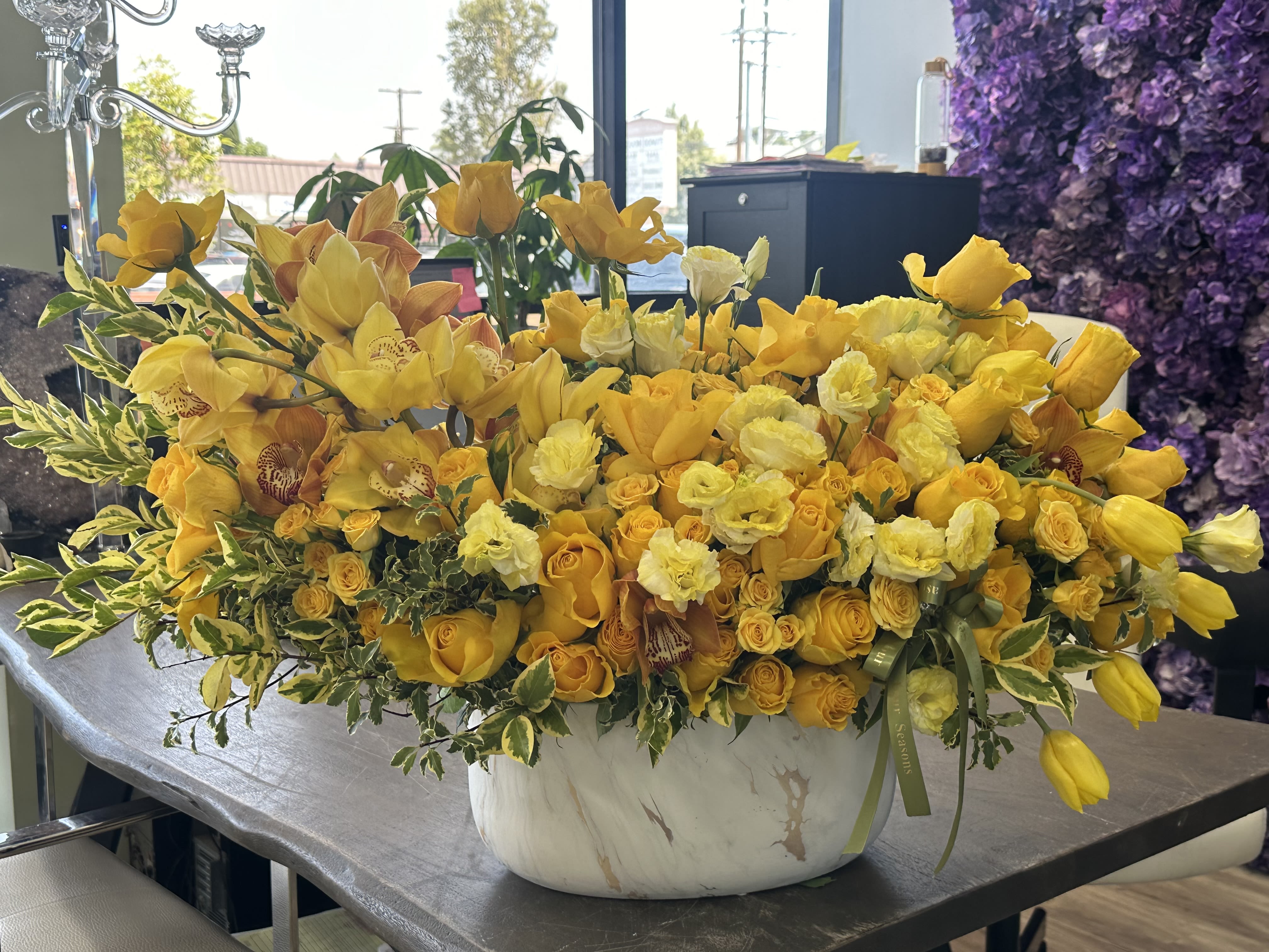 Sunshine Love Sunshine Love - This stunning lush arrangement is modern and timeless at the same time. Different shades of yellow and mix of floral blooms creates texture and a charming ambiance. The deep yellow hues of the roses are complimented by the soft yellow orchids, lisianthus and tulips. Delicate touches of charisma are a perfect element with its flecked soft yellow tips making it the most beautiful symphony of sunshine love. Resting in a white marbled vase it is perfect for any occasion Some florals are seasonal, if particular flower will not be available due to season, we will substitute for similar flower, composition, color pallet and value of the arrangements as closely as possible. All effort to create a floral arrangement as close to the photo shown, the actual arrangement may vary slightly in its appearance from the photo shown. If you have any questions about your order, we welcome you to call us in or email