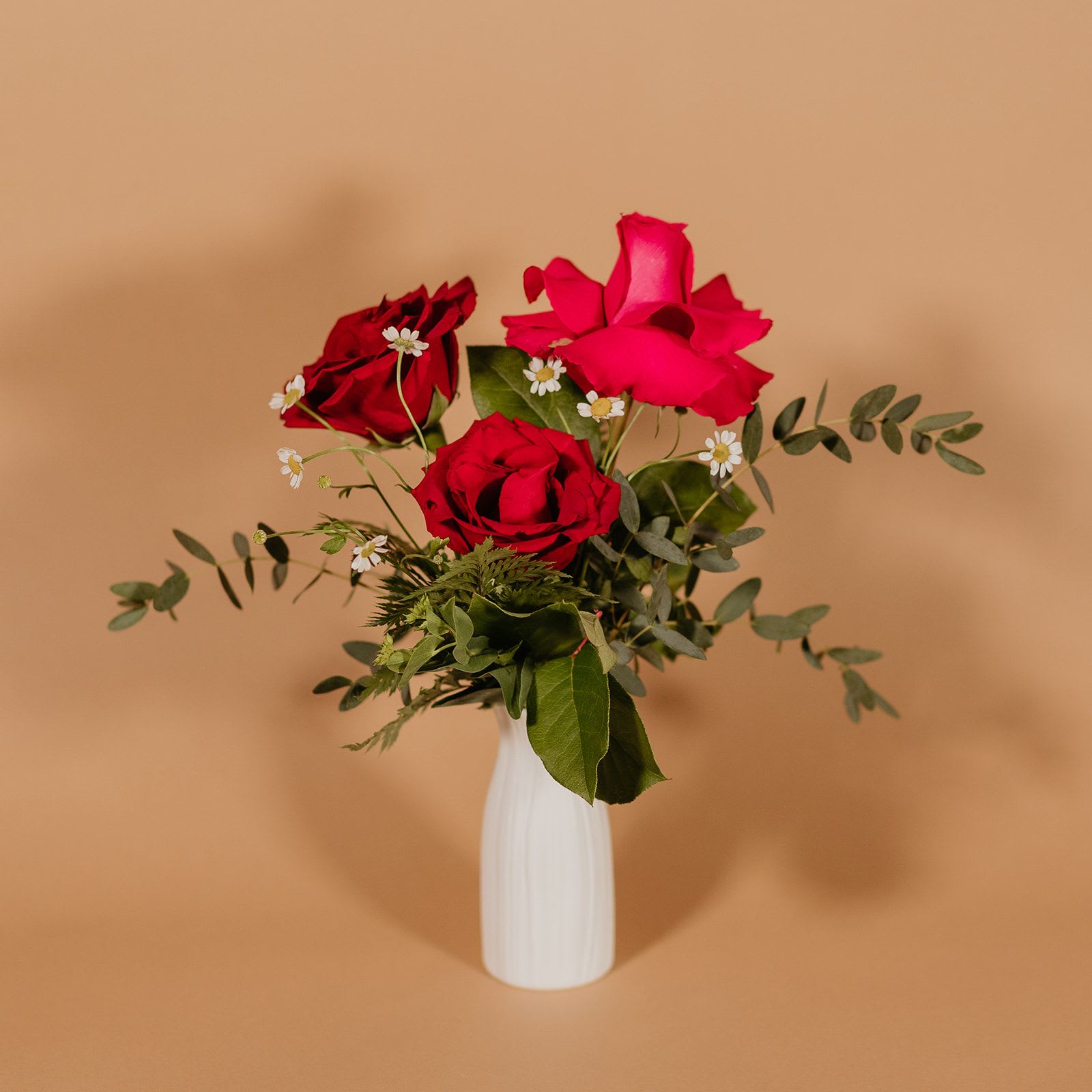 Quarter Dozen Rose Design - 3 Rose Design  Celebrate love and romance with our stunning trio of roses elegantly nestled in a charming ceramic vase. Each rose is meticulously selected to ensure the utmost quality.   Crafted with artistry, the ceramic vase adds a touch of sophistication to any space, making it a timeless keepsake long after the florals fade into cherished memories.