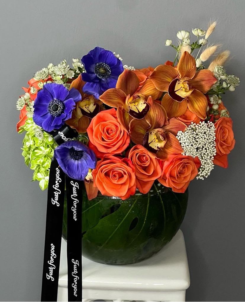 Harmonious blend - Orange roses, exotic orchids and a selection of other seasonal flowers.