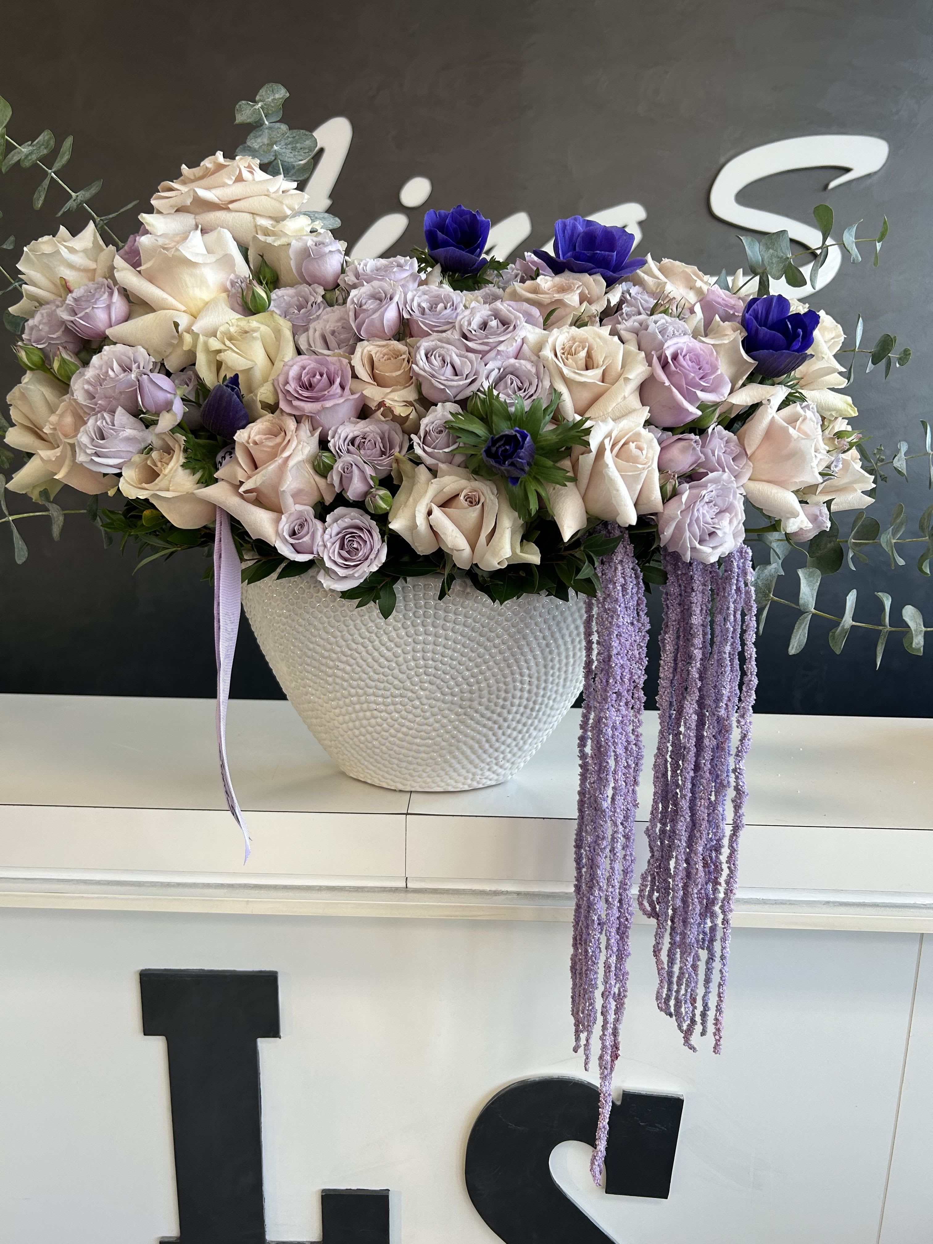 Mary Mary - A combination of purple lavender roses and anemones creates a soft and enchanting arrangement. The lavender roses, symbolizing love, enchantment, and elegance, pair beautifully with anemones, known for their striking contrast of dark centers and delicate petals, adding depth and sophistication to the bouquet.