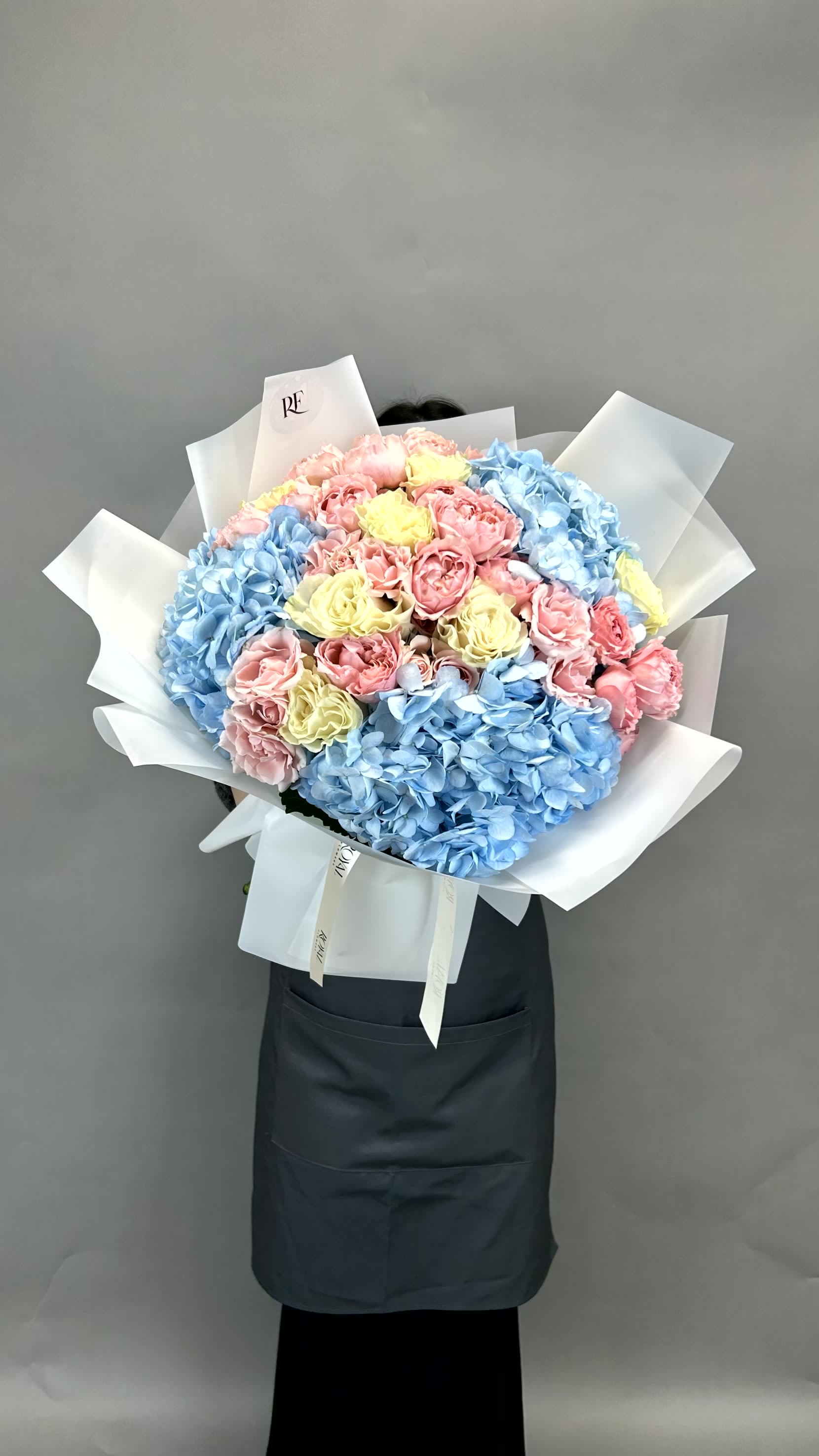Blue Enchantment Blue Enchantment - A stunning duet of blue hydrangeas and Juliette garden spray roses, complemented by premium roses for a touch of romance and charm.