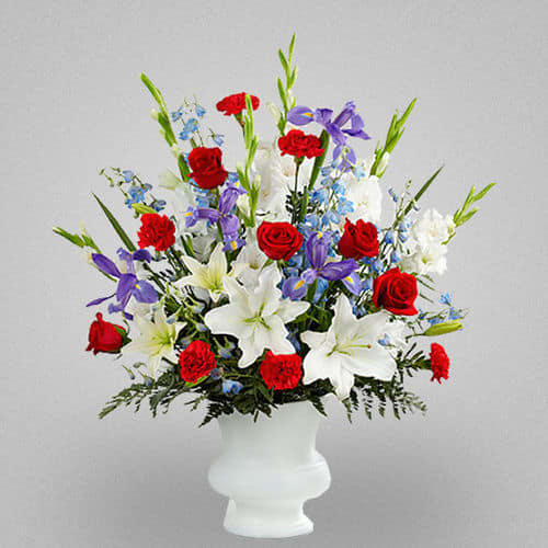 Cherished Love - It is an elegant display, which uses the fresh red, light blue, and white to honor your love at the final farewell service.  Ingredients:  Red roses, red carnations, white gladiolus, light blue delphinium, blue iris, white Oriental lilies, white Asiatic lilies and lush greens  Vase: Presented in a white plastic urn.  Size: Approximately 32&quot;H x 24&quot;W