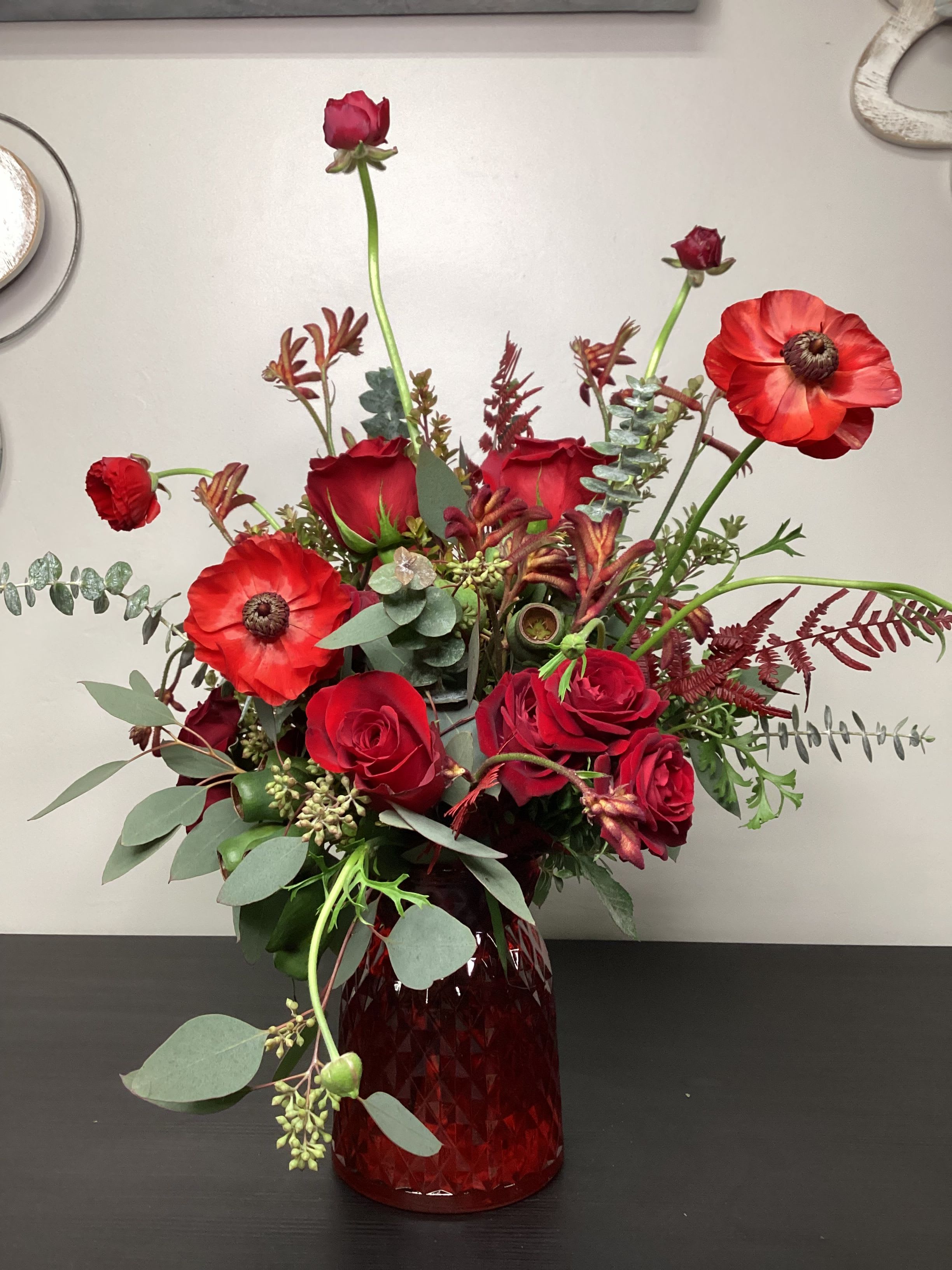 Radiantly Red - A fun mono-shaded collection of vibrant red and burgundy hues, made of the freshest selection of flowers chosen by our design staff. We even added stems of shaped palmetto fans in glittering gold to really make a statement.