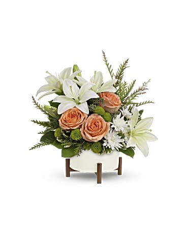 Teleflora's Mod Blooms Bouquet - Unique in every way, this striking bouquet of peach roses and white lilies is artfully presented in a mid-mod ceramic planter with sculptural wood base. Peach roses, white asiatic lilies, green button spray chrysanthemums and white button spray chrysanthemums are arranged with grevillea, variegated pittosporum, lemon leaf and seeded eucalyptus. Delivered in Teleflora's Mid-Century planter. Orientation: All-Around  SUBSTITUTION POLICY – Always deliver the freshest flowers! Please note the bouquet pictured reflects our original design.  If the exact flowers or container in this arrangement are not available, we will create a beautiful bouquet with the freshest available flowers.