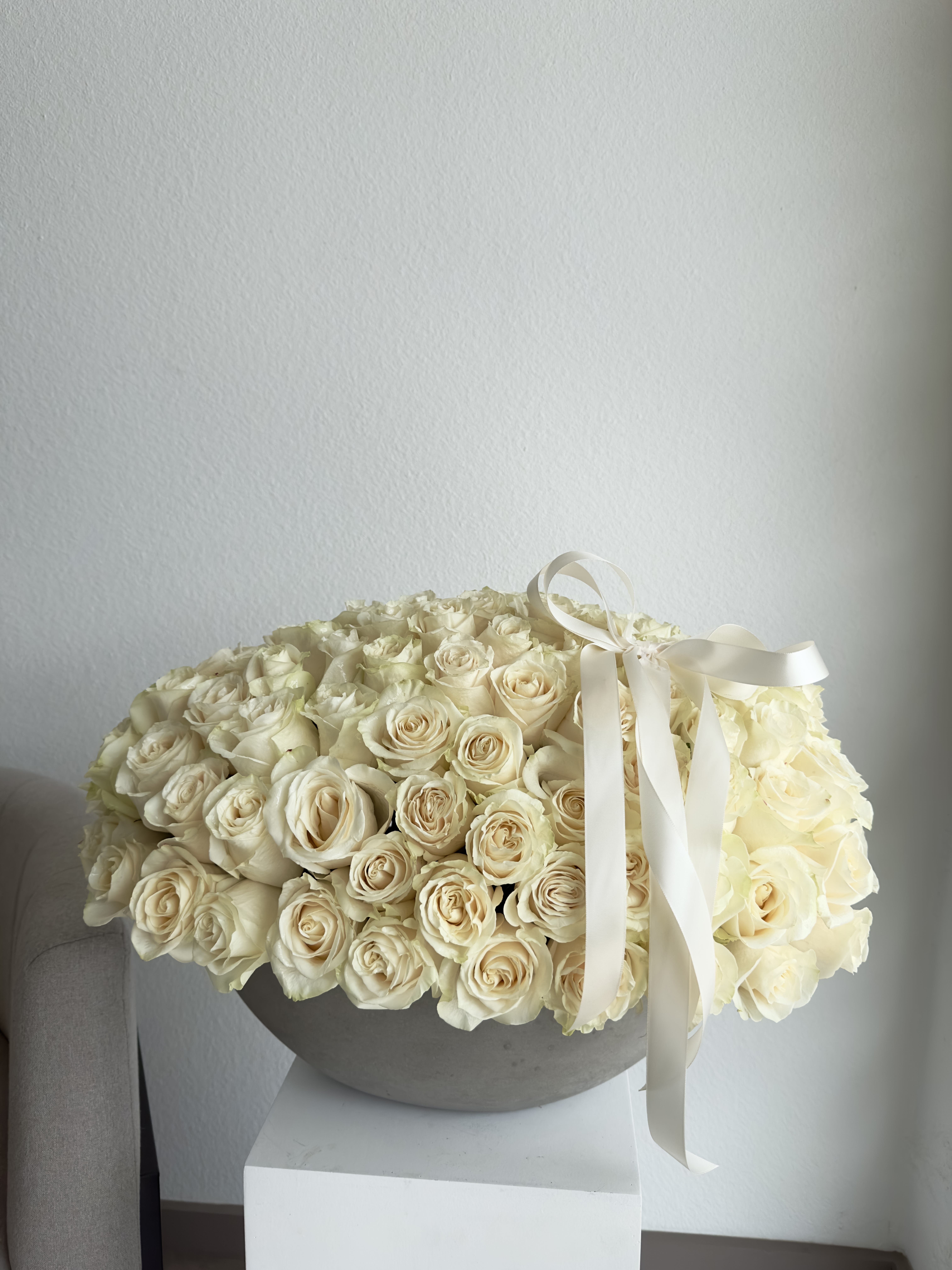 Ethereal Elegance - 100-125 WHITE ROSES   This breathtaking arrangement includes white roses.  Perfect for any occasion.  Arrangement includes:  CONCRETE BOAT VASE Custom greeting card