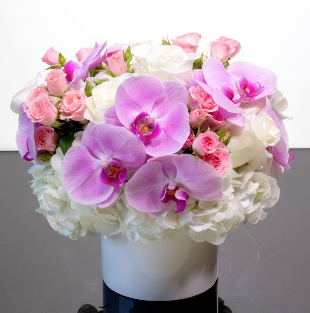 So Cute - A sweet mix of pastel roses, hydrangea and orchids arranged in a ceramic vase.