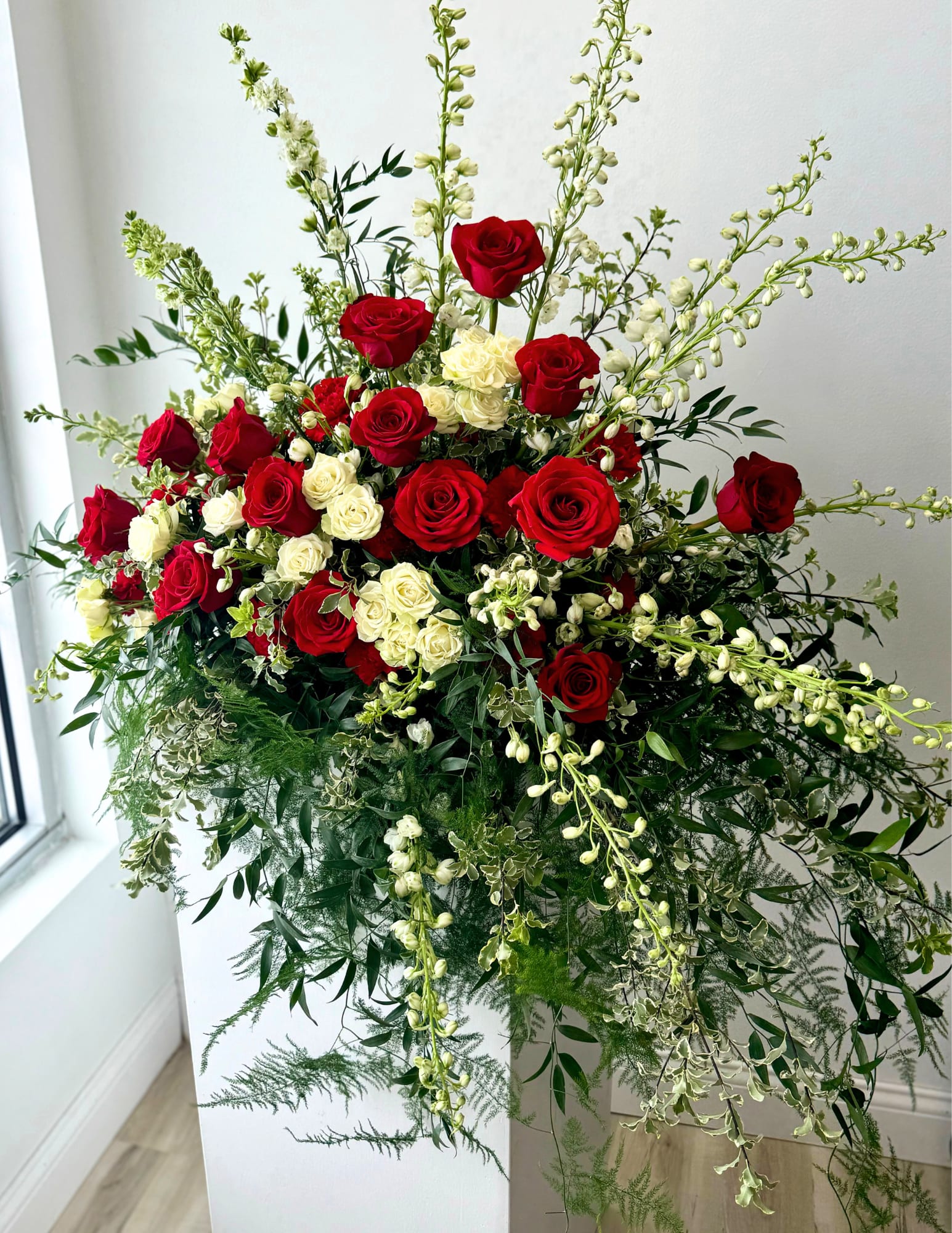 RED &amp; WHITE CASKET SPRAY - A graceful red and white funeral arrangement symbolizes love and remembrance. Featuring elegant white and bold red blooms, offering comfort and peace during a time of loss