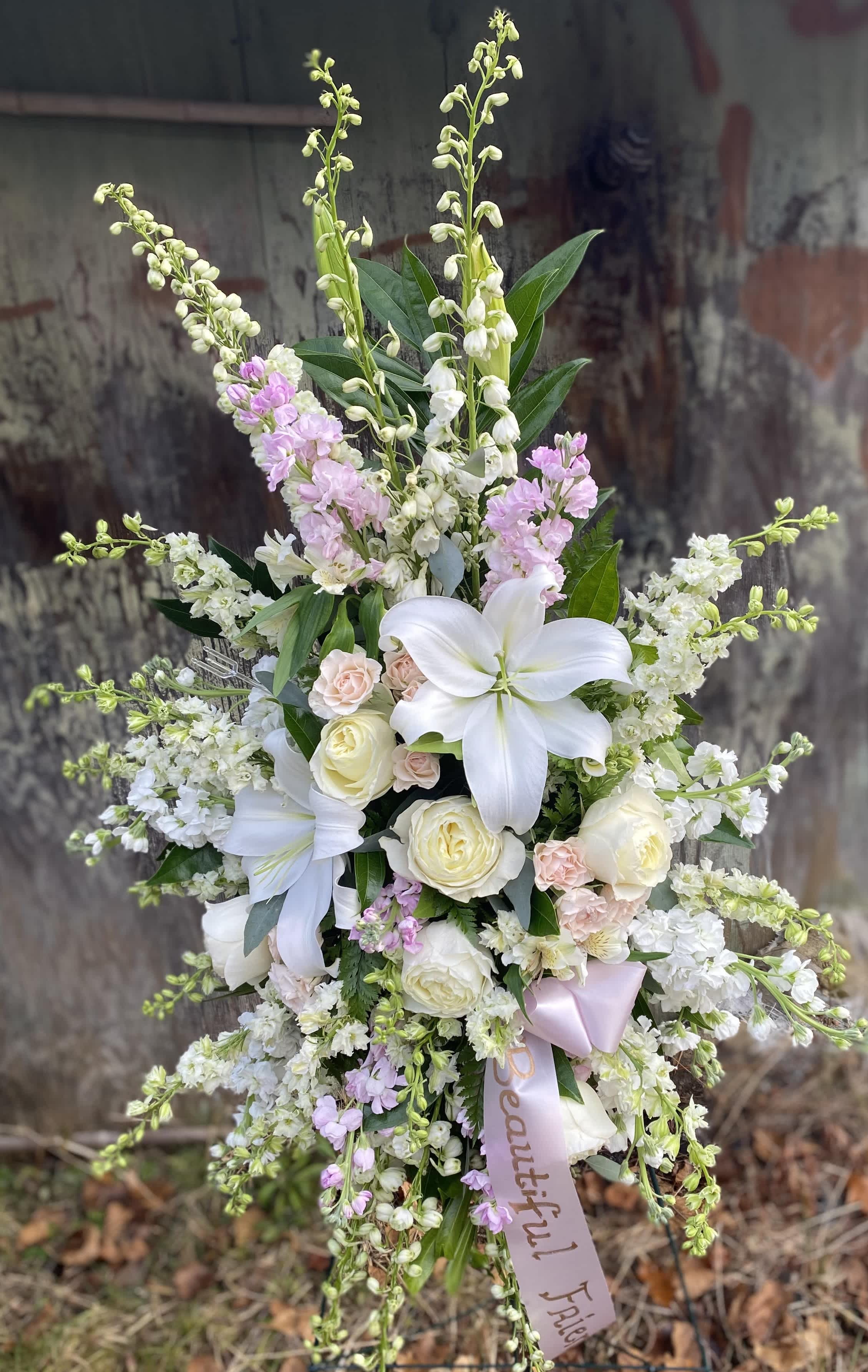 Pastel Standing Spray - This standing spray is made up of delphinium, stock, larkspur, roses, lilies, and mini carnations with a customizable ribbon. 