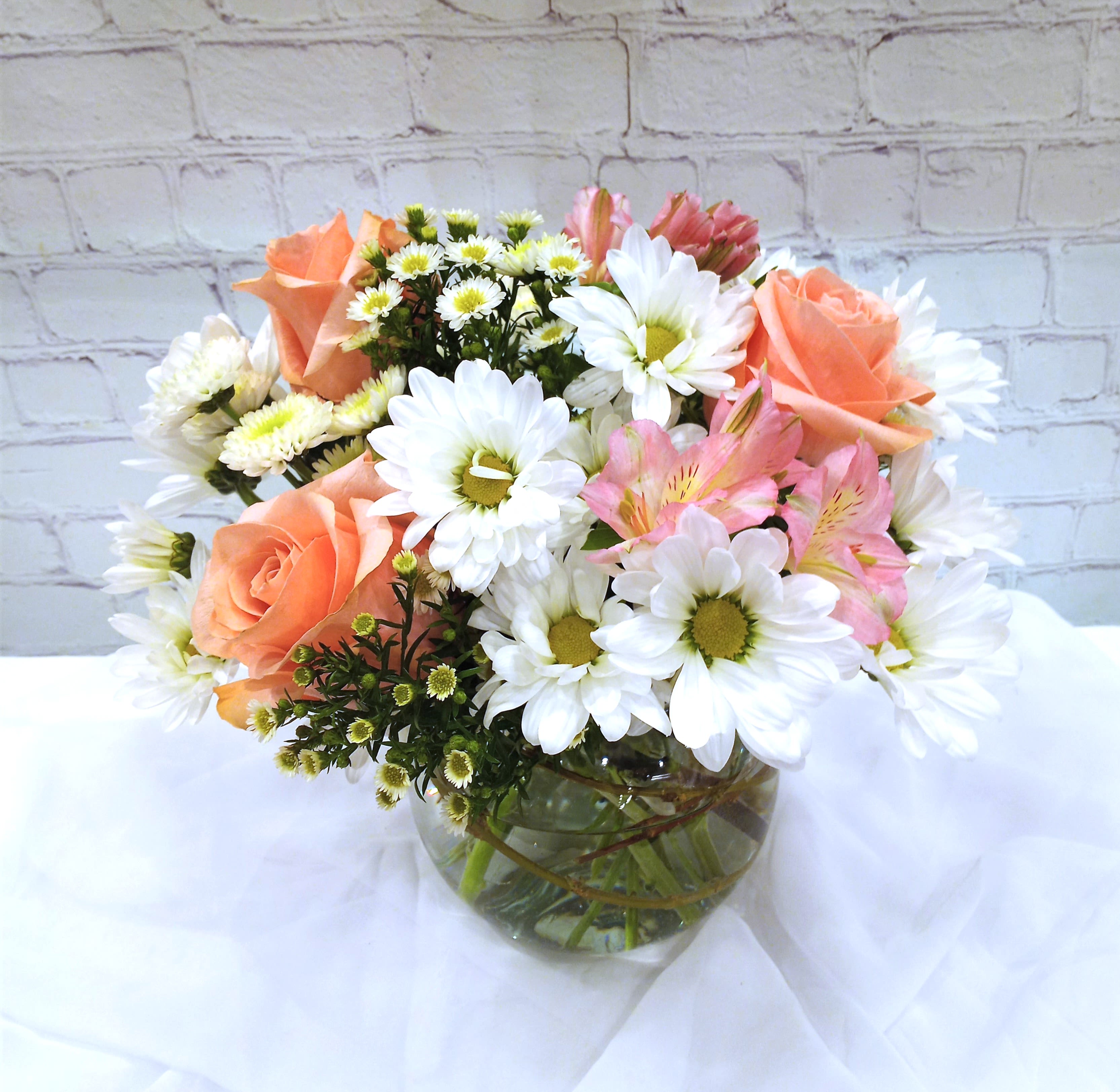 Daisy delightful - A light and airy daisy centerpiece in a clear bowl.  Coral reef roses, pink alstroemeria and spray asters.  A summer refresher.   Approximate size 8&quot; high x 7&quot; wide