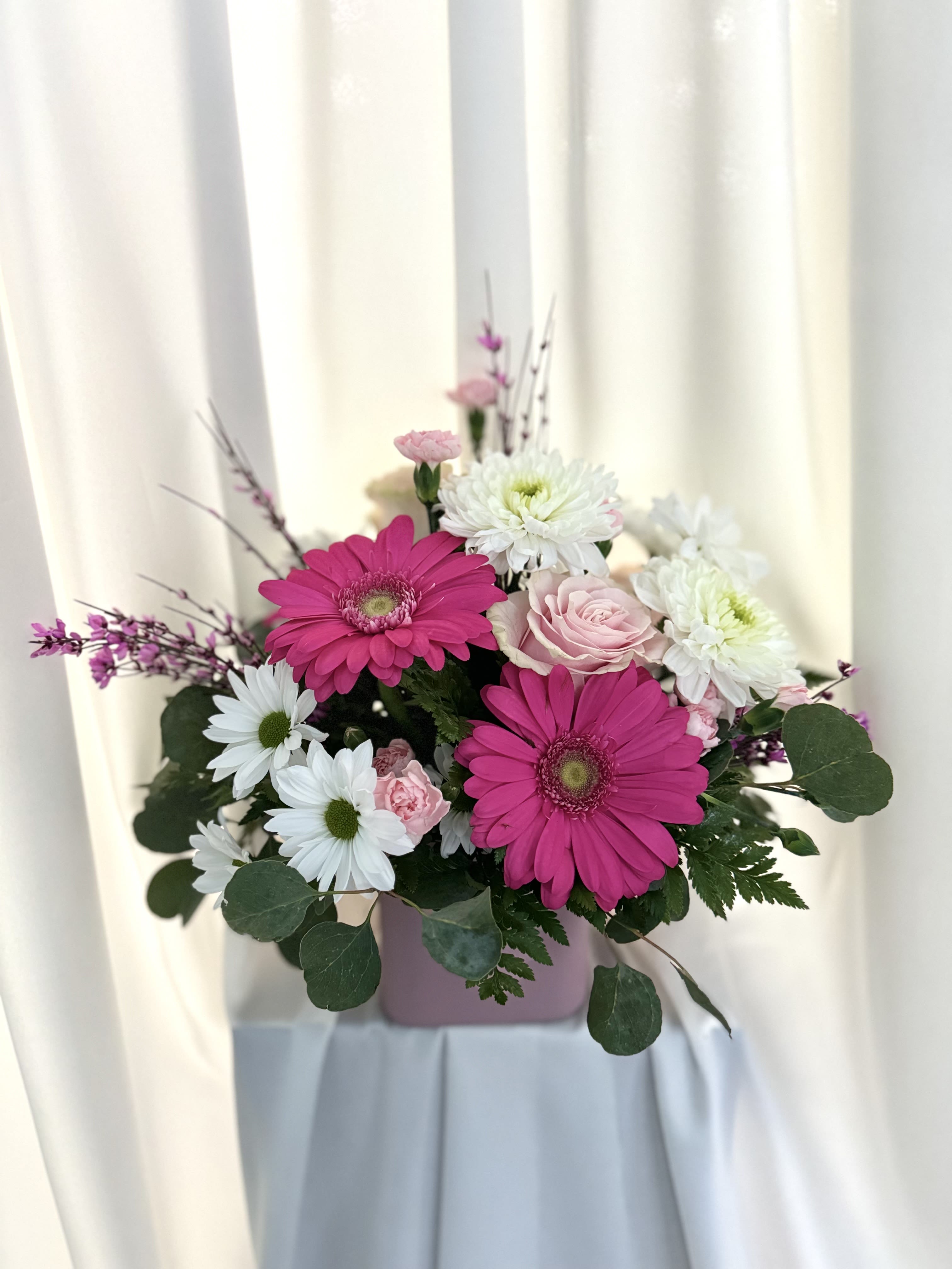 Pink Elegance Pink Elegance - This vibrant floral arrangement features bold pink gerbera daisies, delicate white daisies, and soft pink roses accented with lush greenery. Perfect for brightening any room or celebrating a special occasion, it exudes charm and elegance in every bloom.