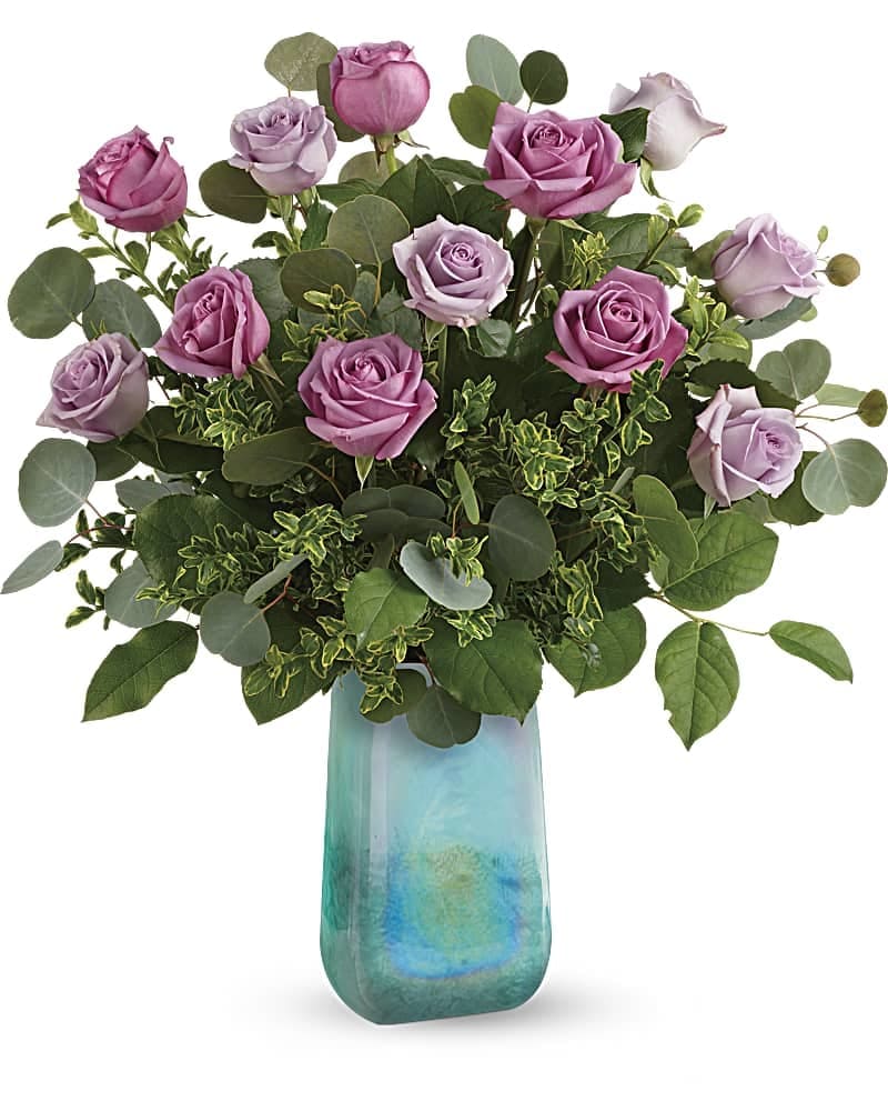 Teleflora's Watercolor Roses Bouquet - Like a wondrous watercolor painting, this soothing gift of 12 soft lavender roses in a hand-blown, iridescent art glass vase is a breathtaking reminder of your love on Mother's Day. This gorgeous bouquet includes 6 lavender roses, 6 light lavender roses, silver dollar eucalyptus, oregonia and lemon leaf. Delivered in an Art Glass Treasure vase.