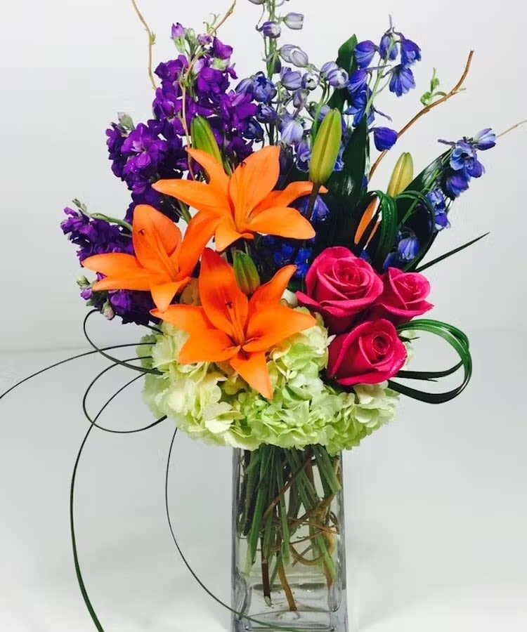 Vertical Brightness - A modern arrangement filled with green hydrangea, pink roses, purple stock, blue delphiniums and orange lilies.