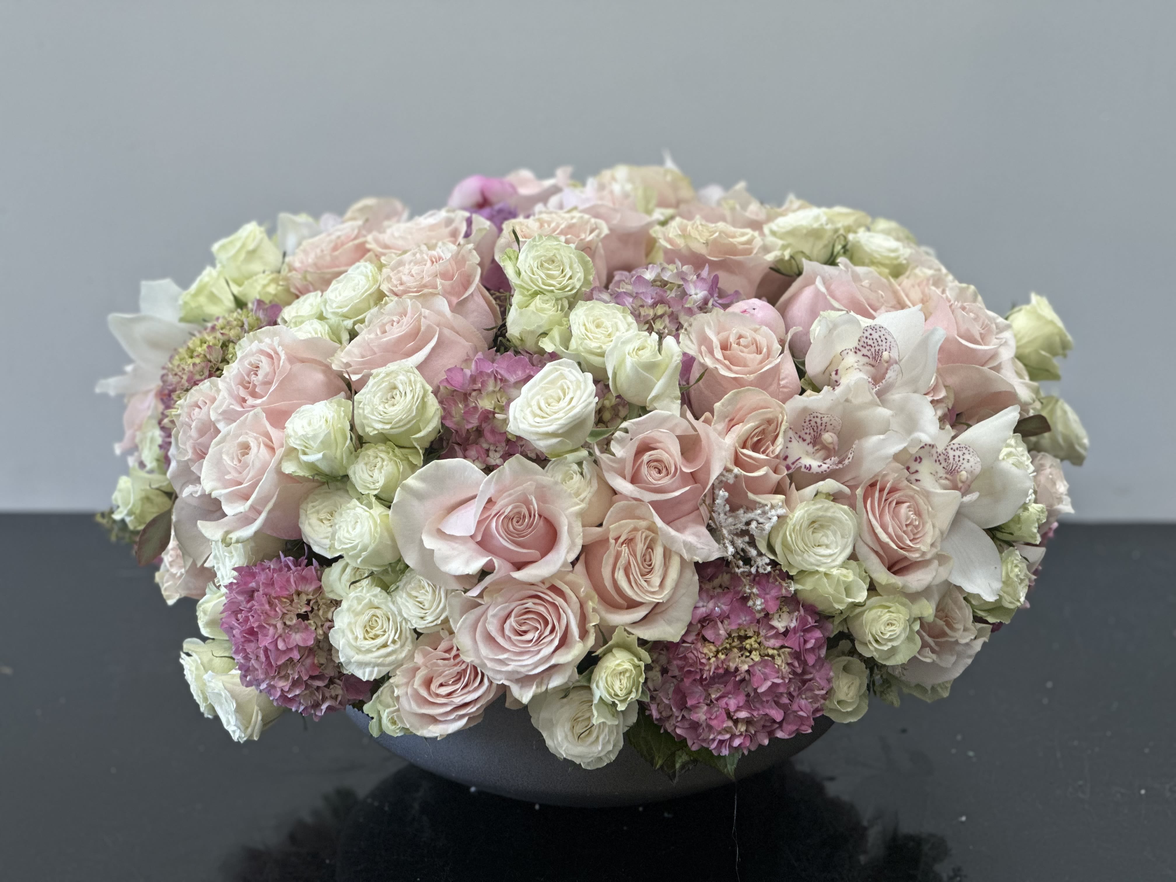 Chloe Chloe - Classical and timeless arrangement lush with blooms. Soft and gentle color pallet of blush pink and white roses in the classical composition. Featuring orchids as a touch of luxurious element with an assortment of pink hydrangeas and lisianthus to complete the elegance of the floral mix. Some florals are seasonal, if particular flower will not be available due to season, we will substitute for similar flower, composition, color pallet and value of the arrangements as closely as possible. All effort to create a floral arrangement as close to the photo shown, the actual arrangement may vary slightly in its appearance from the photo shown. If you have any questions about your order, we welcome you to call us in or email