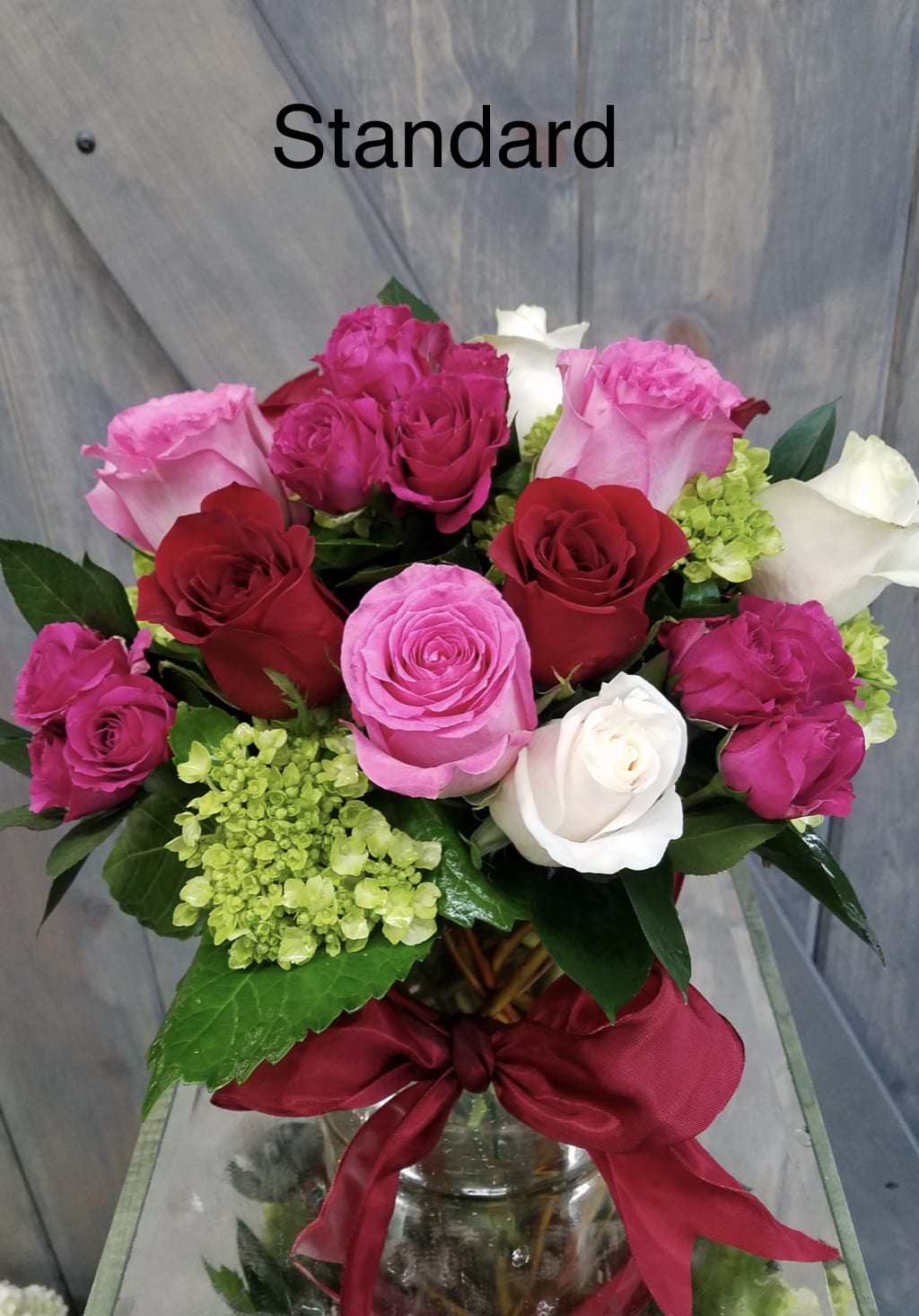Love's Delight - This arrangement is designed with over a dozen roses Red Roses, Pink Roses, White Roses, Hot Pink Spray roses, and including Mini green hydrangea all within a 6&quot; cylinder glass vase