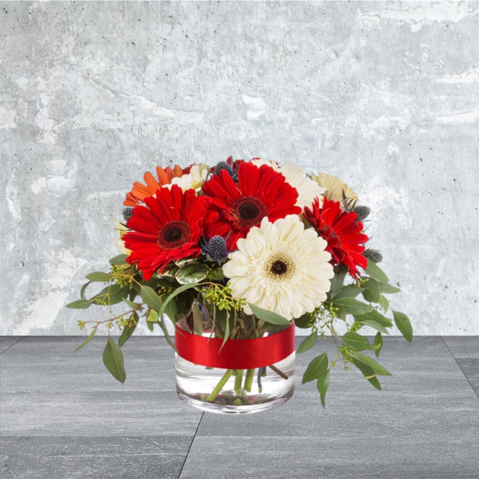 Pop Art - A work of art that stands out, alternating gerbera daisies and a smart red ribbon make this arrangement POP. A perfect gift for any season and any time.  Approximate Dimensions: 12&quot;D x 8&quot;H