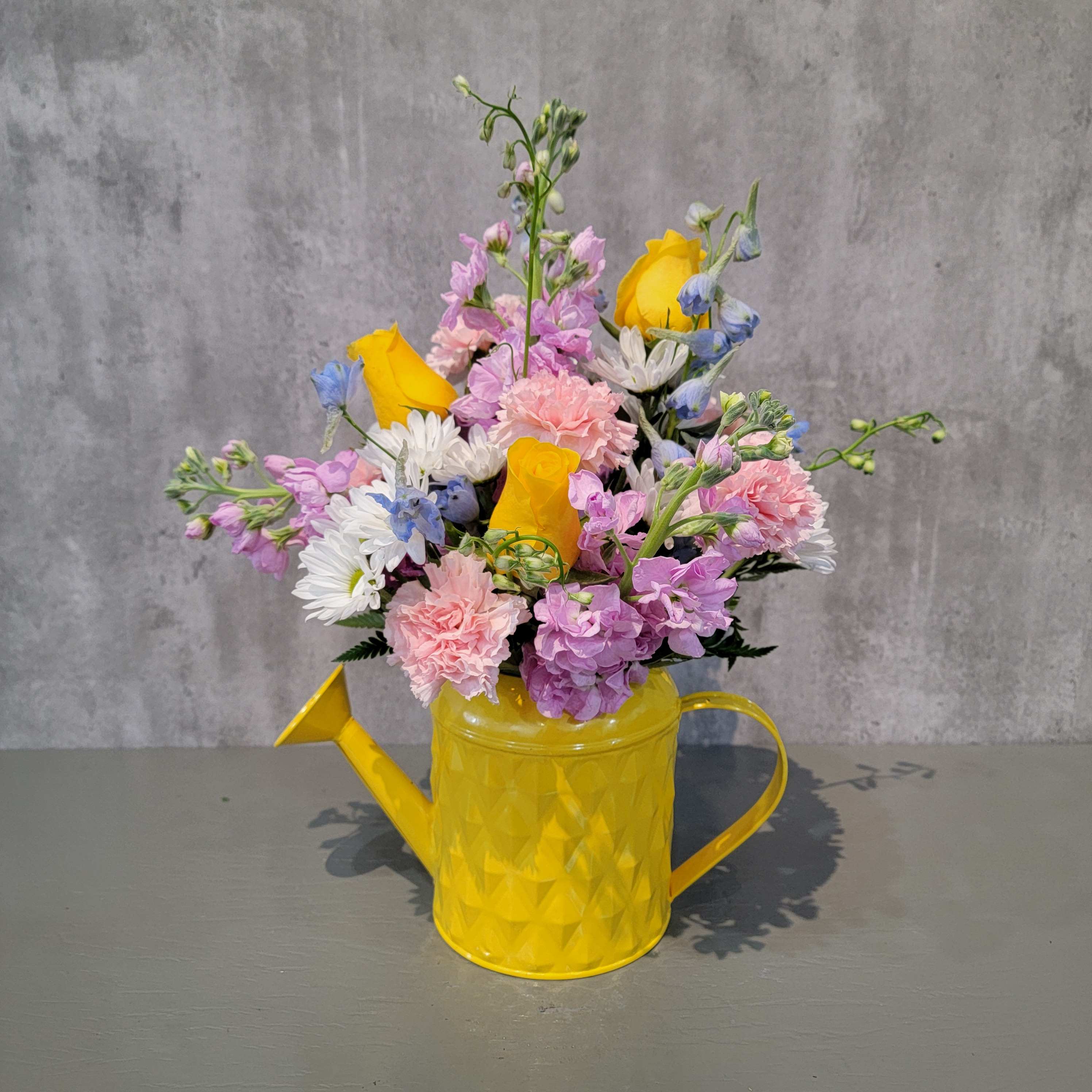 Spring Showers Spring Showers - Spring is in the air! From the pastel colors of these flowers to thee bright yellow of the metal watering can, this bouquet brings thoughts of those April showers to ensure May flowers! The arrangement is approximately 15" tall and 11" wide.