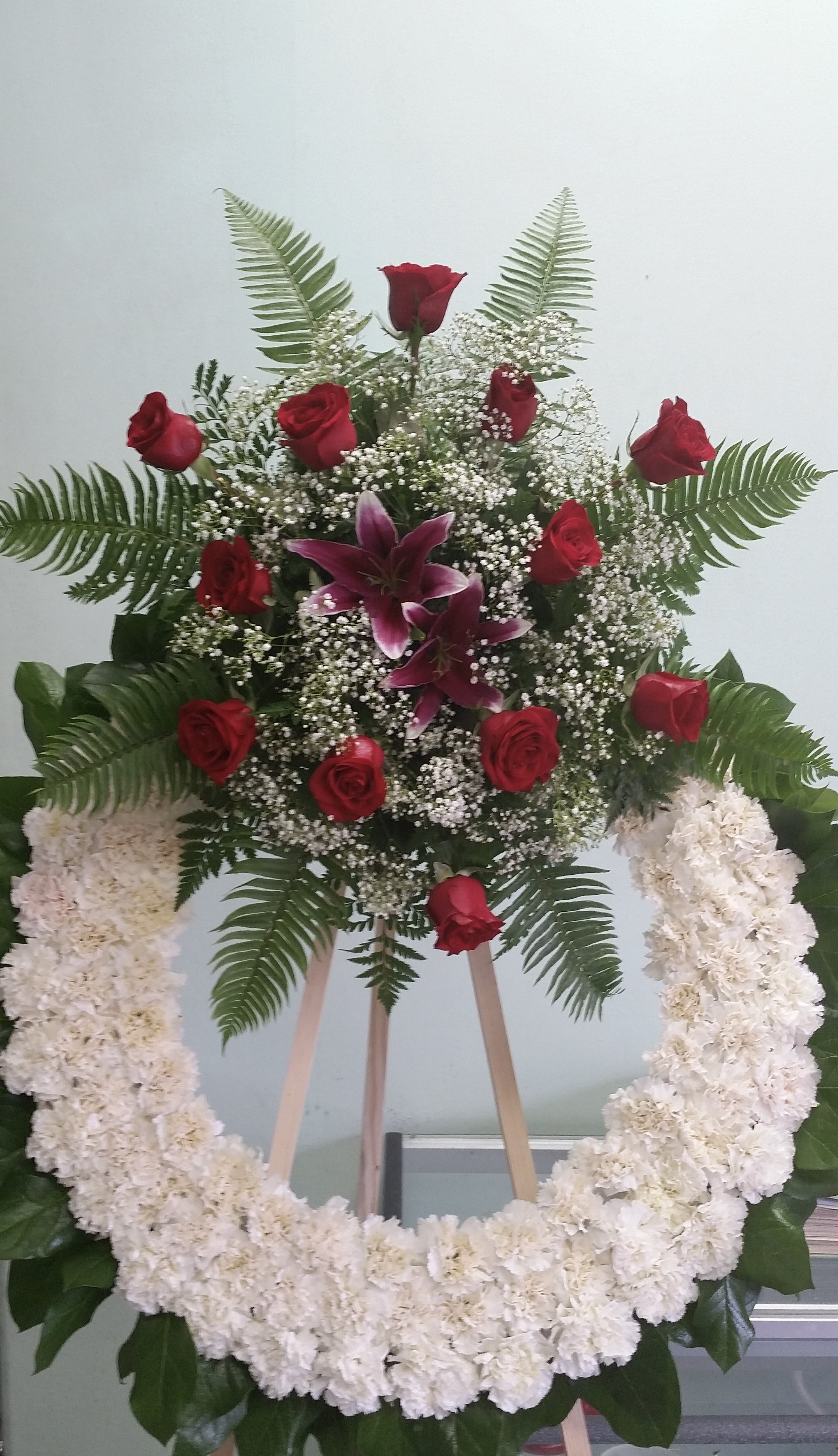 Circle of Hope - Open wreath with white carnations, red roses, and hot pink lilies.