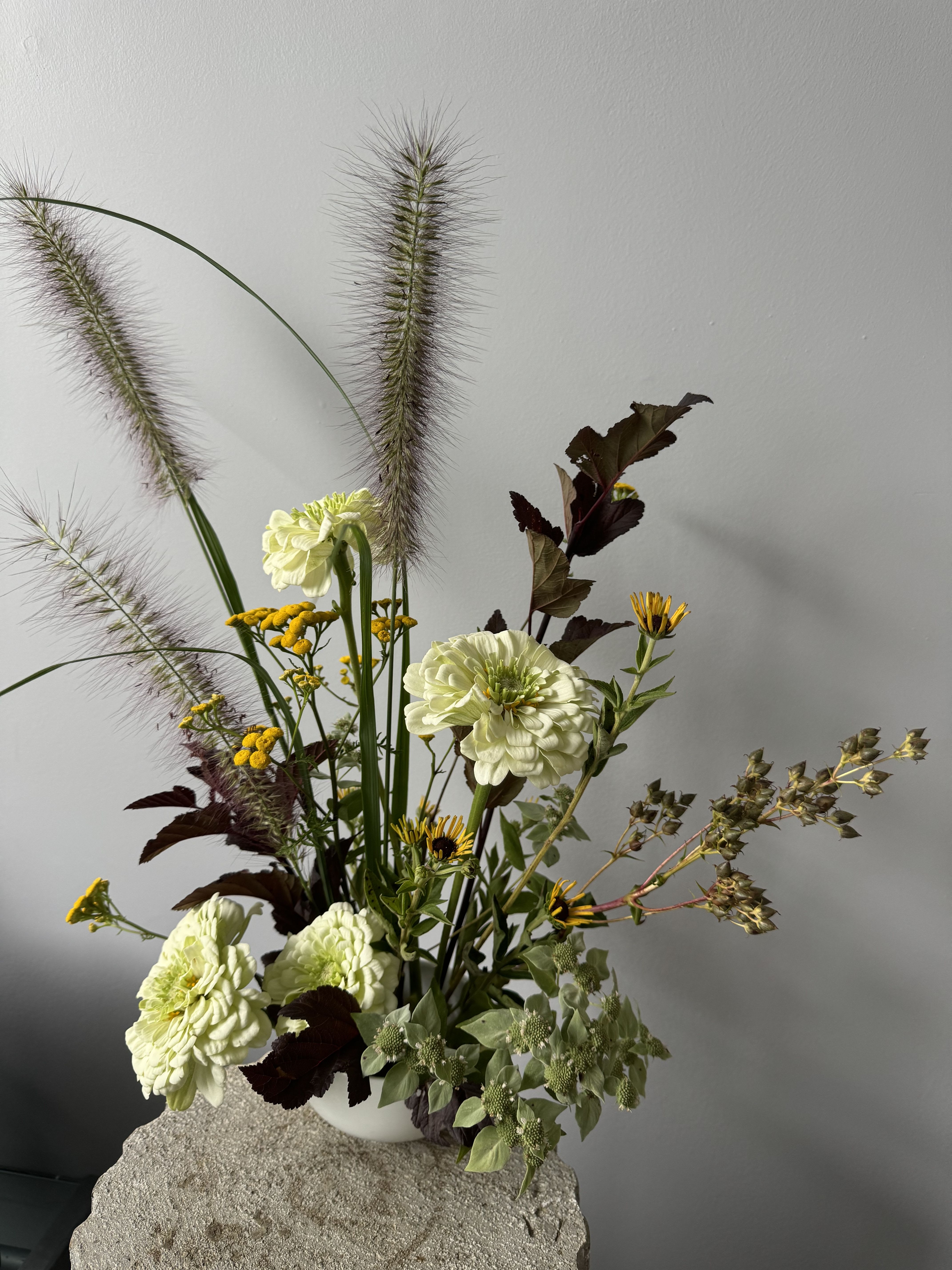 Ikebana Arrangement  - Add a touch of Zen to your space with a beautiful Ikebana arrangement, showcasing seasonal blooms and colors that encapsulate nature’s beauty. Each piece is carefully crafted by hand, ensuring it’s one-of-a-kind and perfect for brightening up your home. Order now for a unique floral experience delivered right to your door.  It comes in a beautiful, handmade ceramic lotus container, which can be reused for your own Ikebana practice or brought back to our shop to be refilled with fresh flowers.  Ikebana, the Japanese art of flower arranging, focuses on balance, simplicity, and the fleeting beauty of nature. It’s not just an arrangement, but a peaceful connection to the seasons and a moment of quiet reflection.