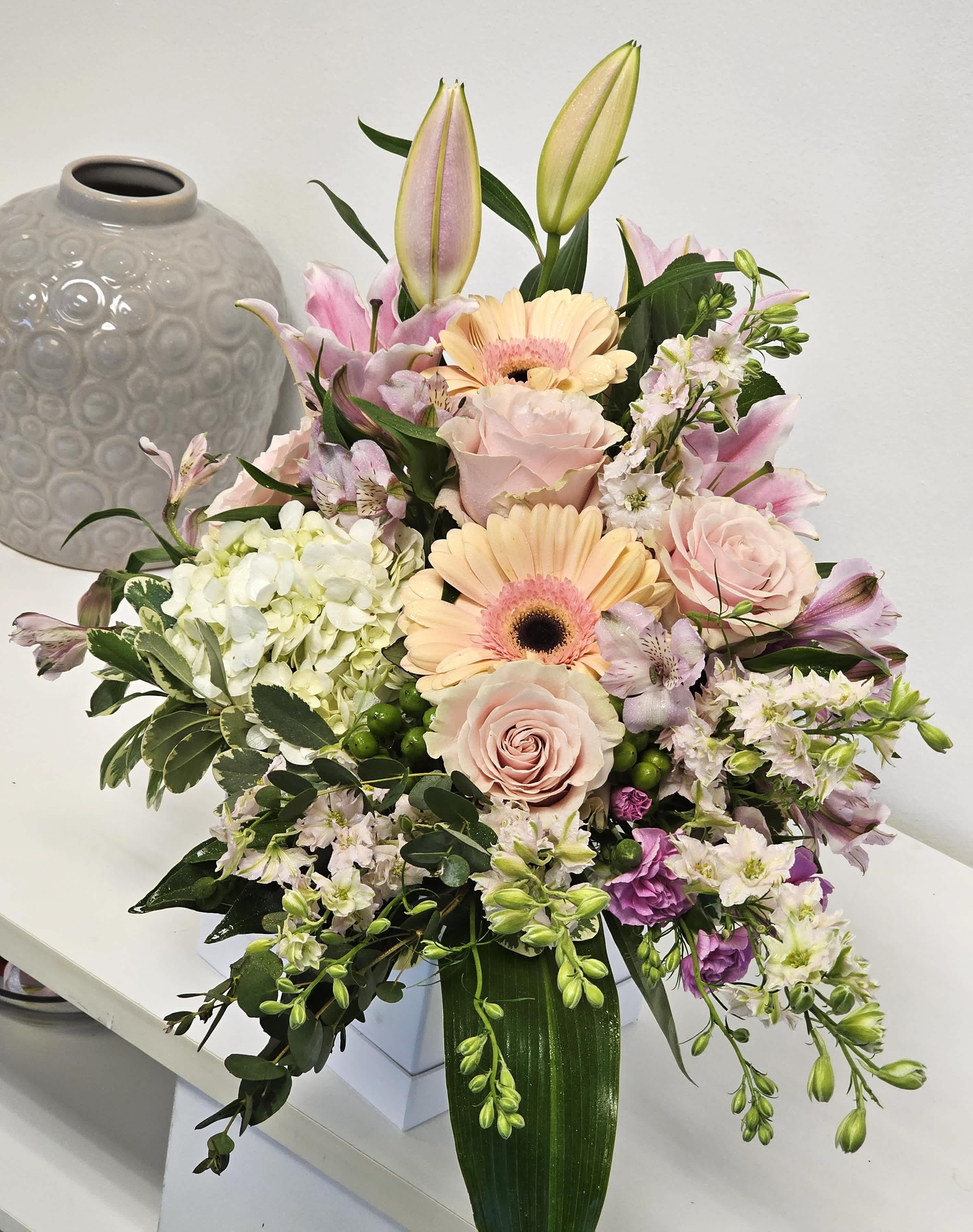 Delicate Arrangement - Our Delicate Sympathy Arrangement gracefully combines soft, pastel blooms, offering a gentle and heartfelt tribute to honor the memory of a loved one. This tender display brings comfort and peace, embodying love and compassion during times of sorrow.