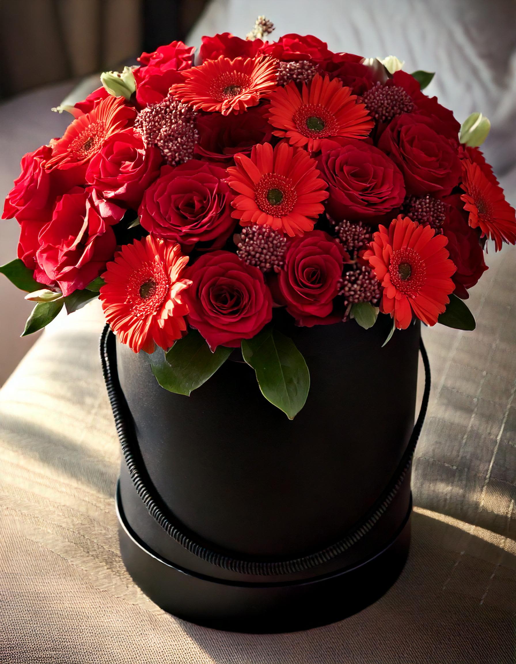 The Verse - Delight in the beauty of our black hatbox packed with lush red roses and Gerberas. Ideal for expressing love and appreciation, this sophisticated arrangement speaks volumes.