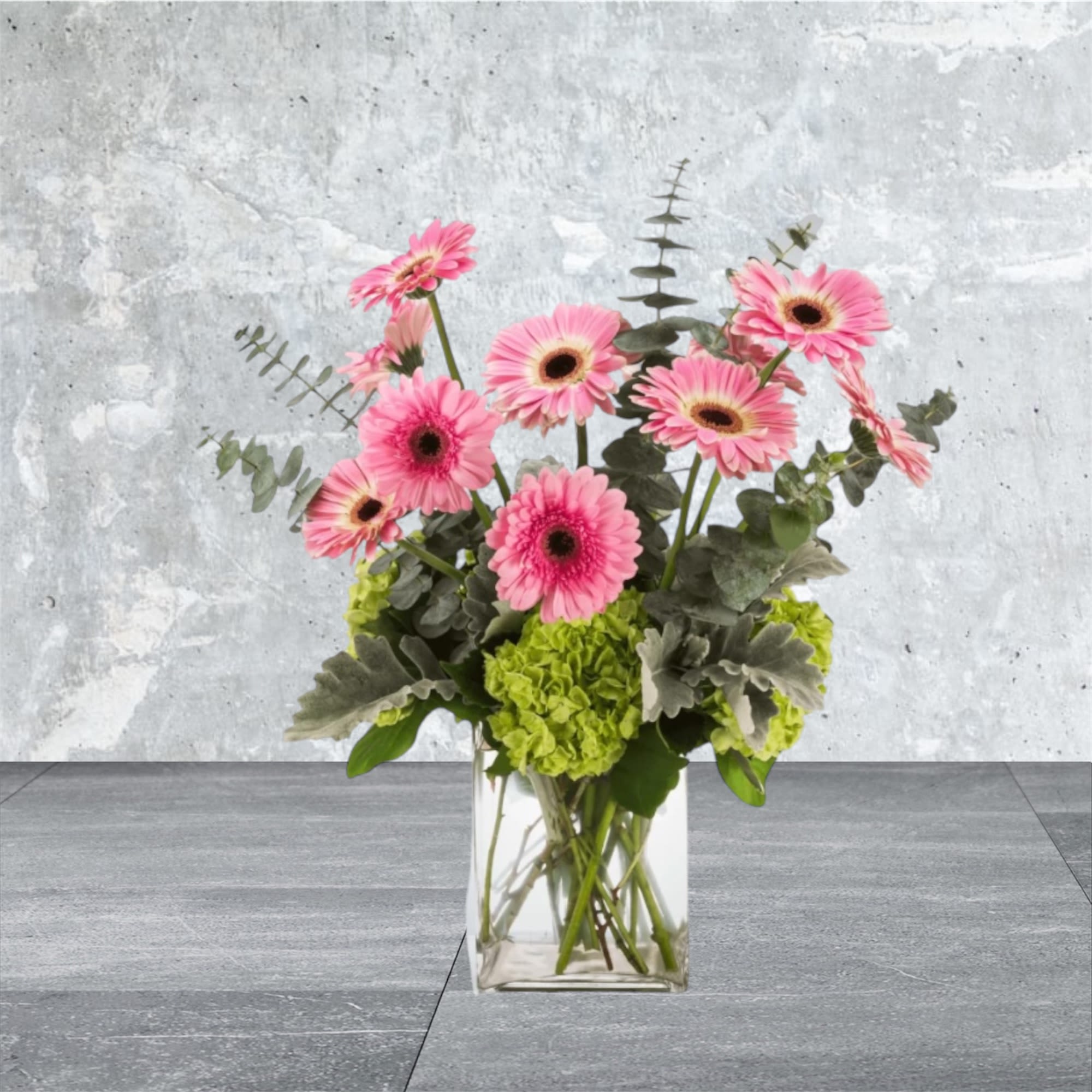 Isn't She Something - This tall standing arrangement is a little bit sassy, a little bit springy. Featuring pink gerbera daisies and spiral eucalyptus it makes everything a little more joyful! Send this to somebody who likes things a little more funky and fun. 