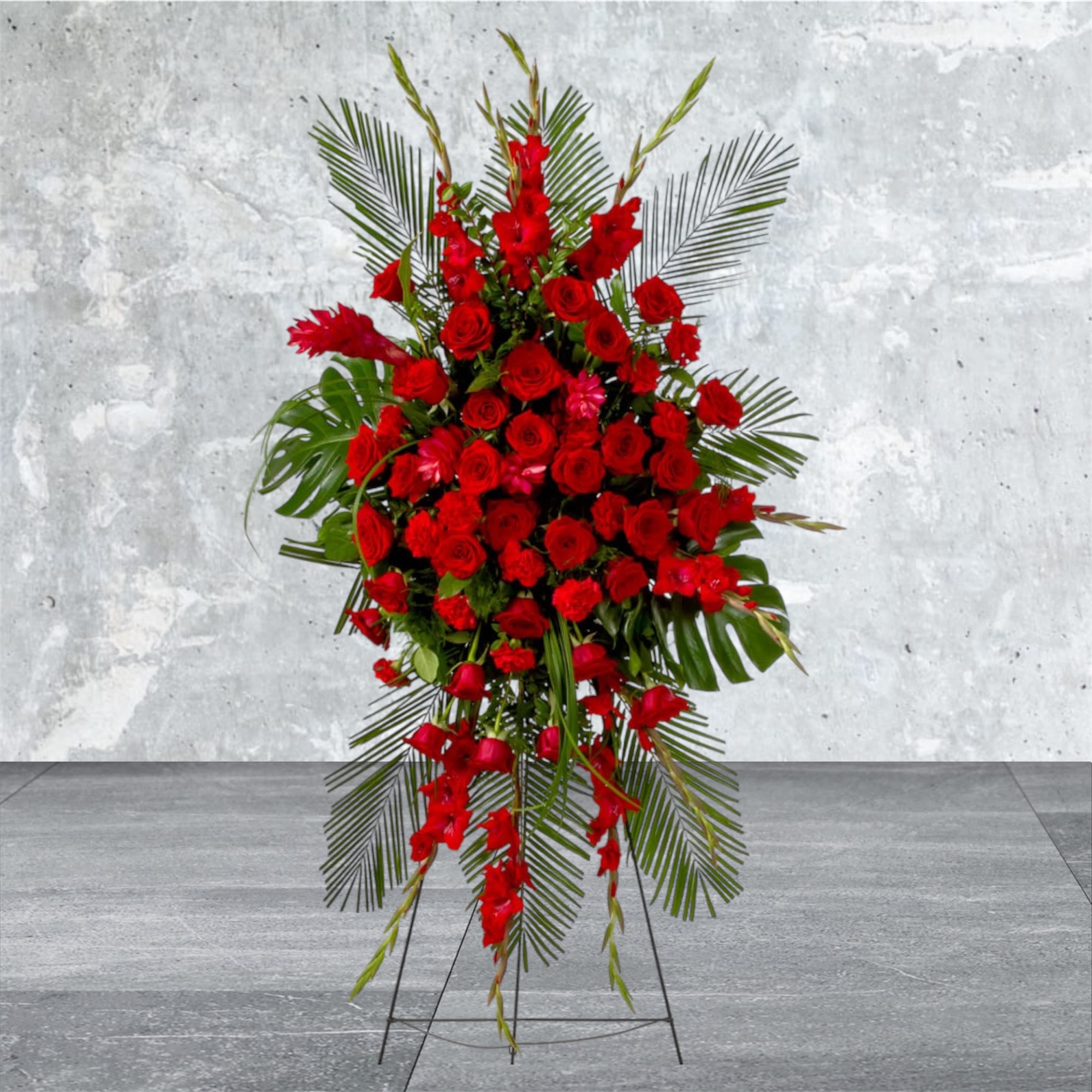Forever Feelings - Red is the color of love and this standing spray displays it with luxurious style. Red roses and palms come together with other red and greenery to create a beautiful salute.