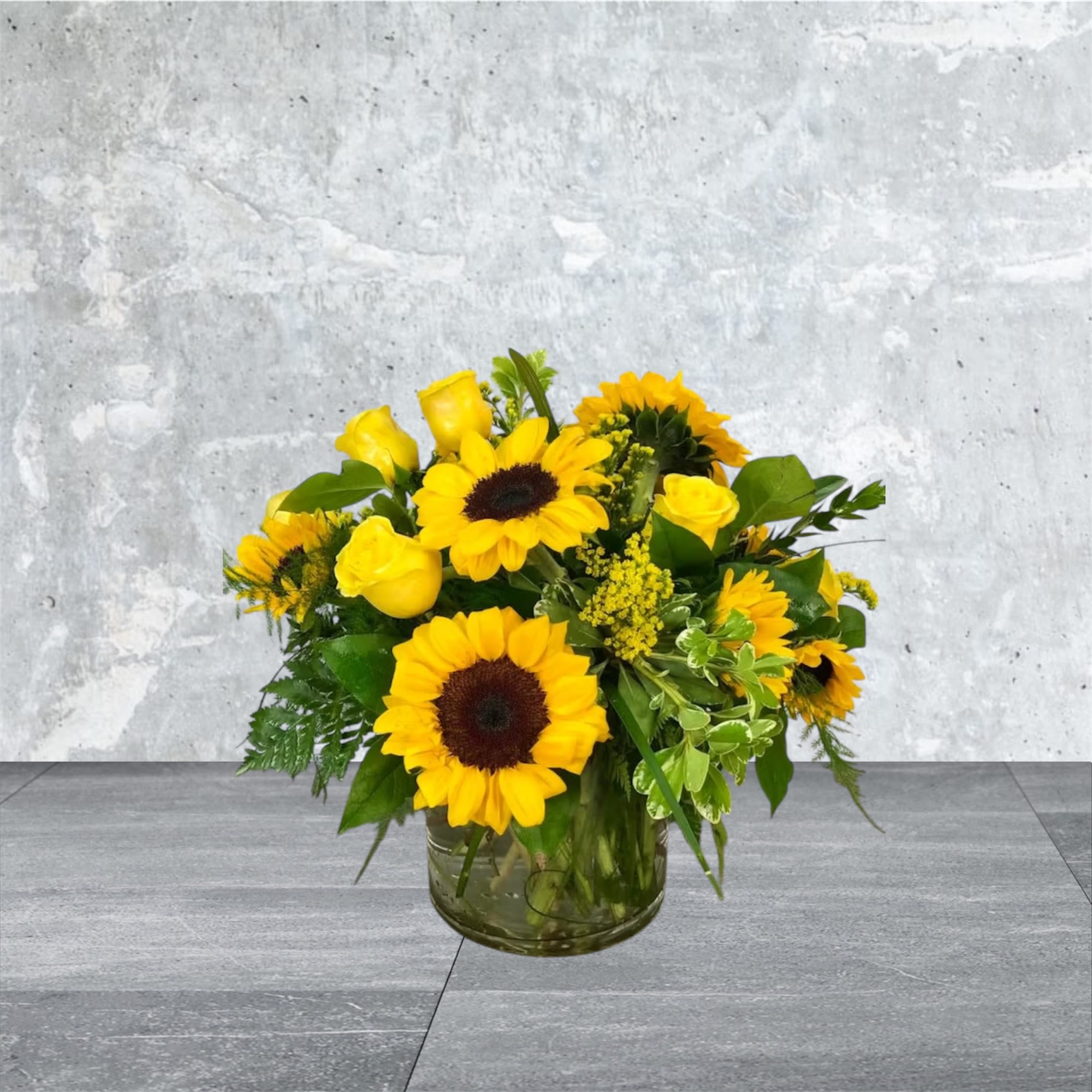 Fellow Yellow - It’s the Fellow Yellow and it's being delivered right to your door! This arrangement boasts 9 sunflowers, 9 roses, and beautiful yellow solidago in between all in a clear glass container, designed to be viewed from any side. Would make a wonderful dinner centerpiece or for your beautiful mother's coffee table!