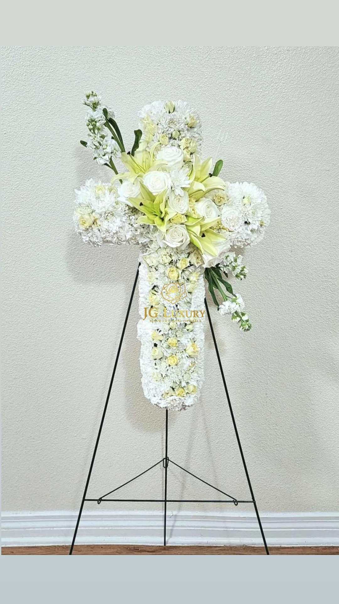 White Cross  - An all white tribute, this white cross funeral spray is pure and tranquil. Featuring a variety of white flowers, this elegant easel compliments the beauty of life. 