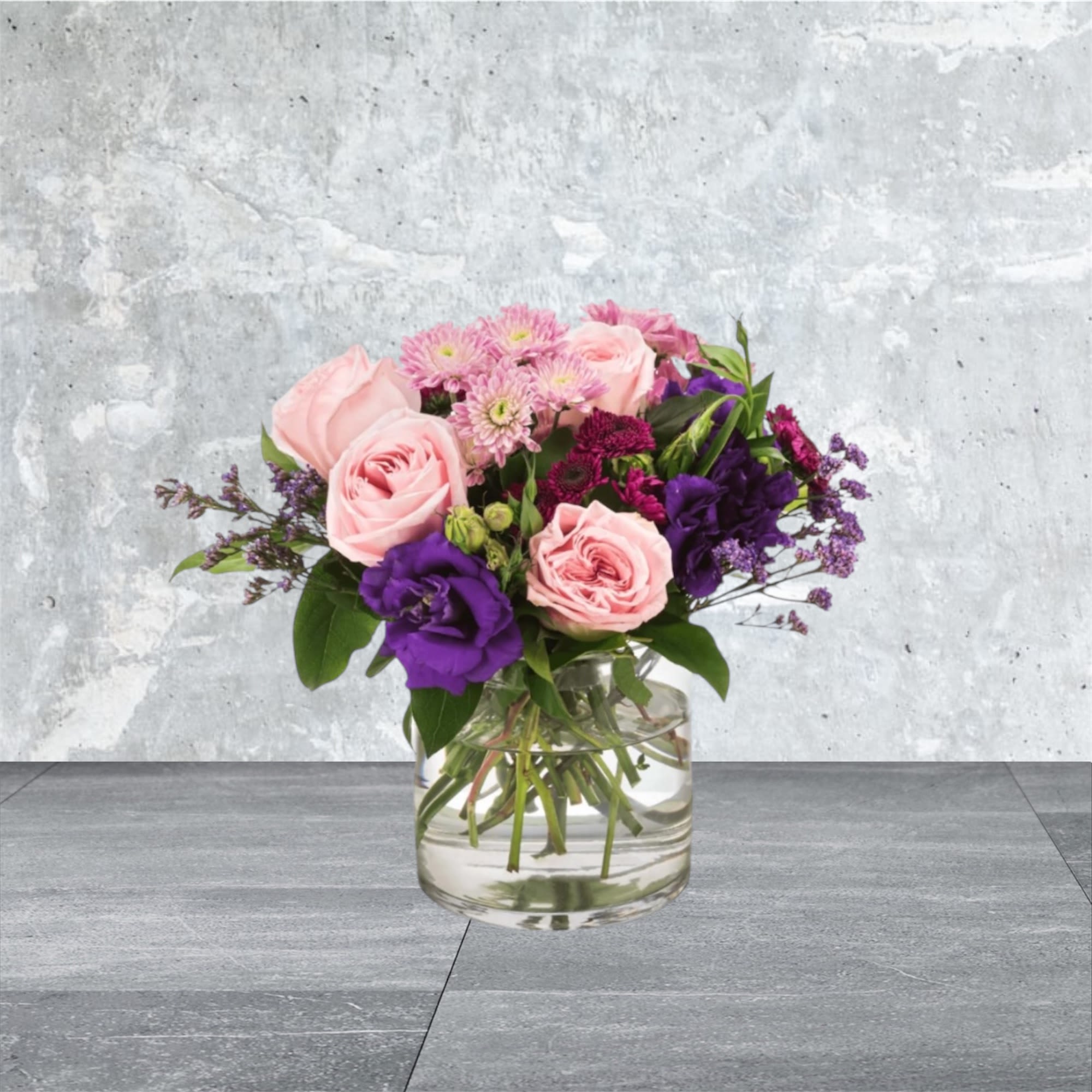 Coming Home - A selection of pink and purple flowers come together in an eye-pleasing arrangement. This arrangement makes a great gift for Mother's Day, Women's Day, or as a thinking of you present.  Approximate Dimensions: 10''D x 10''H
