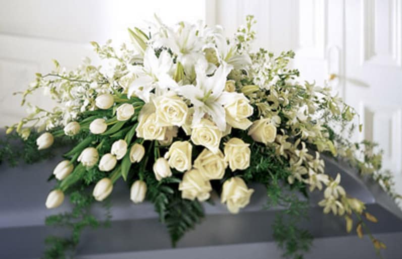 Resurrection Casket Spray - Resplendent and with pure white roses, tulips, orchids and lilies, this spray is an elegant and sophisticated display - A tasteful celebration of the life of your loved one.