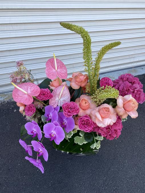 Over The Moon For You - This arrangement is filled with roses, garden roses, anthurium, phalaenopsis orchid, hydrangea,  monstera leaf, and other textural blooms. If you are looking for a wow statement piece this is the arrangement for you!