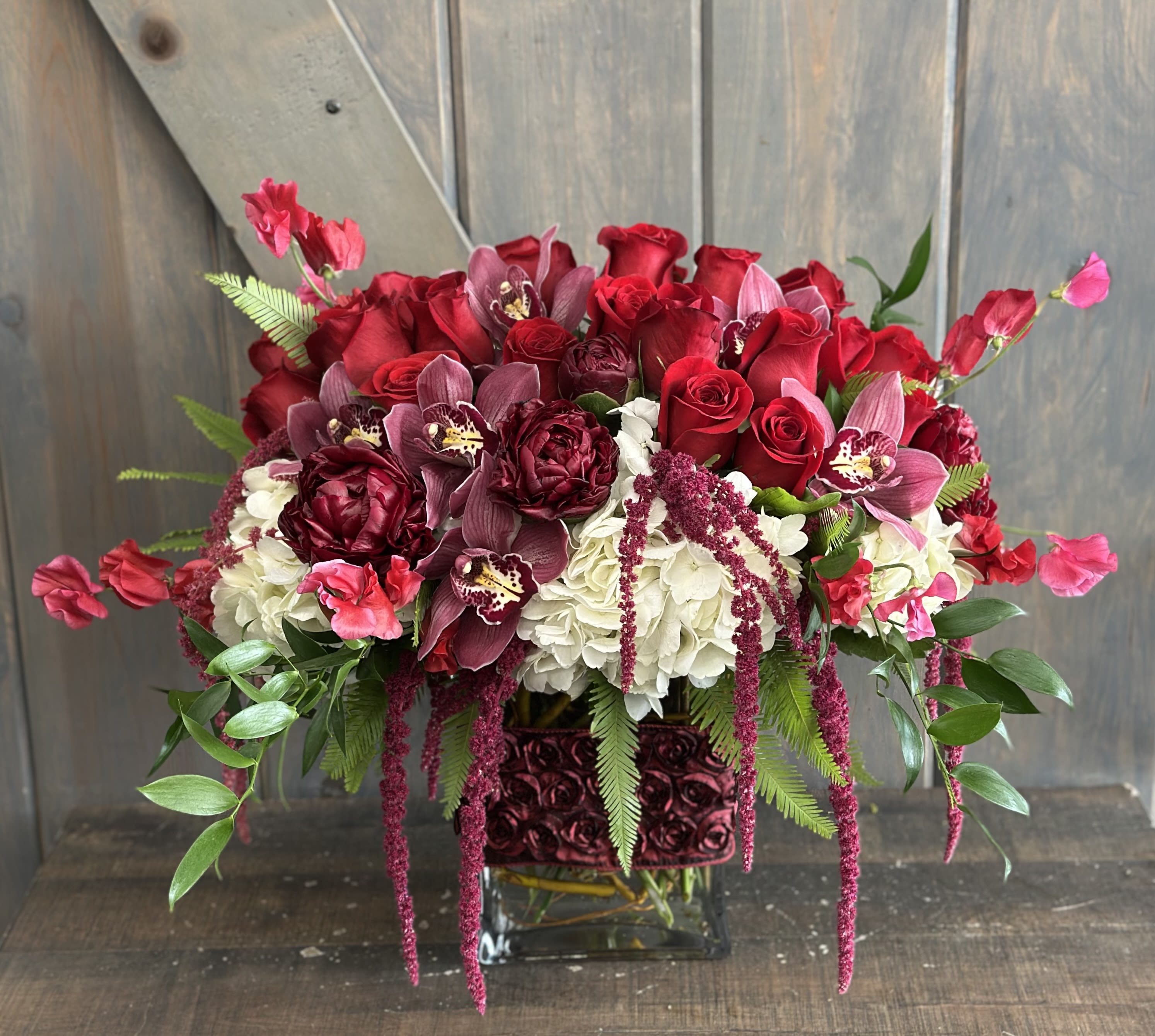 Elegant Romance - This stunning display is lush and romantic. Flowers included in this arrangement are Roses, Peonies, Hydrangea, Sweet Peas, Cymbidium Orchids, and Hanging Amaranthus.