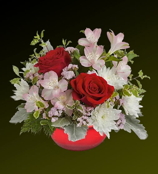 The Romance of Love - Light up your Valentine's Day with this romantic bouquet displayed in a unique red bowl lantern with a decorative handle. This enchanting arrangement features bold red roses, delicate light pink alstroemeria, crisp white poms, and soft pink filler flowers, accented by silvery dusty miller and lush greenery. The lantern doubles as a charming keepsake, making this gift a perfect way to express love and brighten your special someone's day.