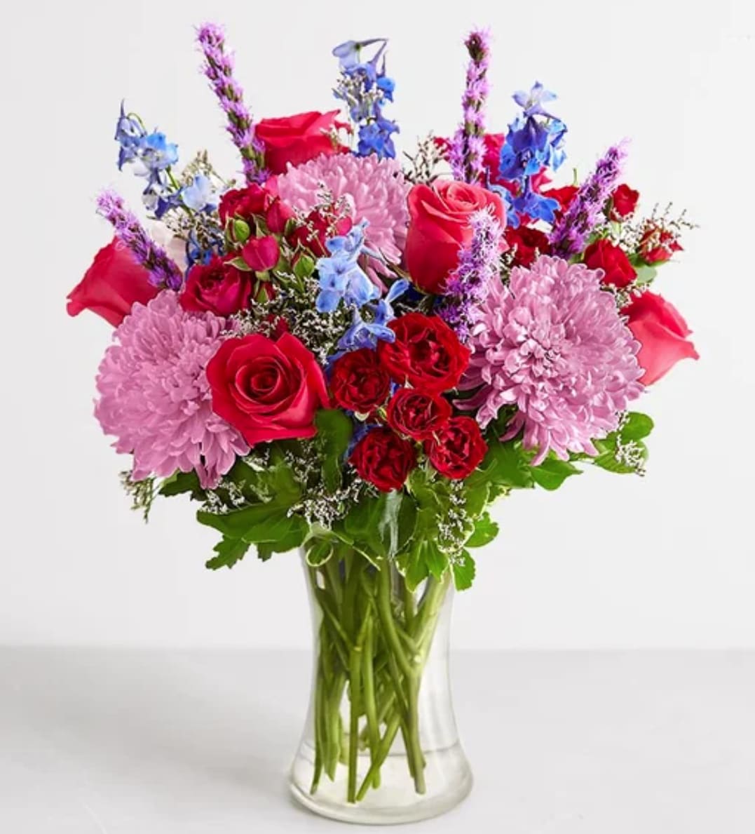 Brillant Beauty™ Bouquet - Color their world and brighten their mood with this medley of blooms and hues. Roses, delphiniums, and other flora in a rainbow of reds, pinks, blues, and violets make this bouquet a wonderful way to commemorate a milestone or transform an ordinary day into an extraordinary one.