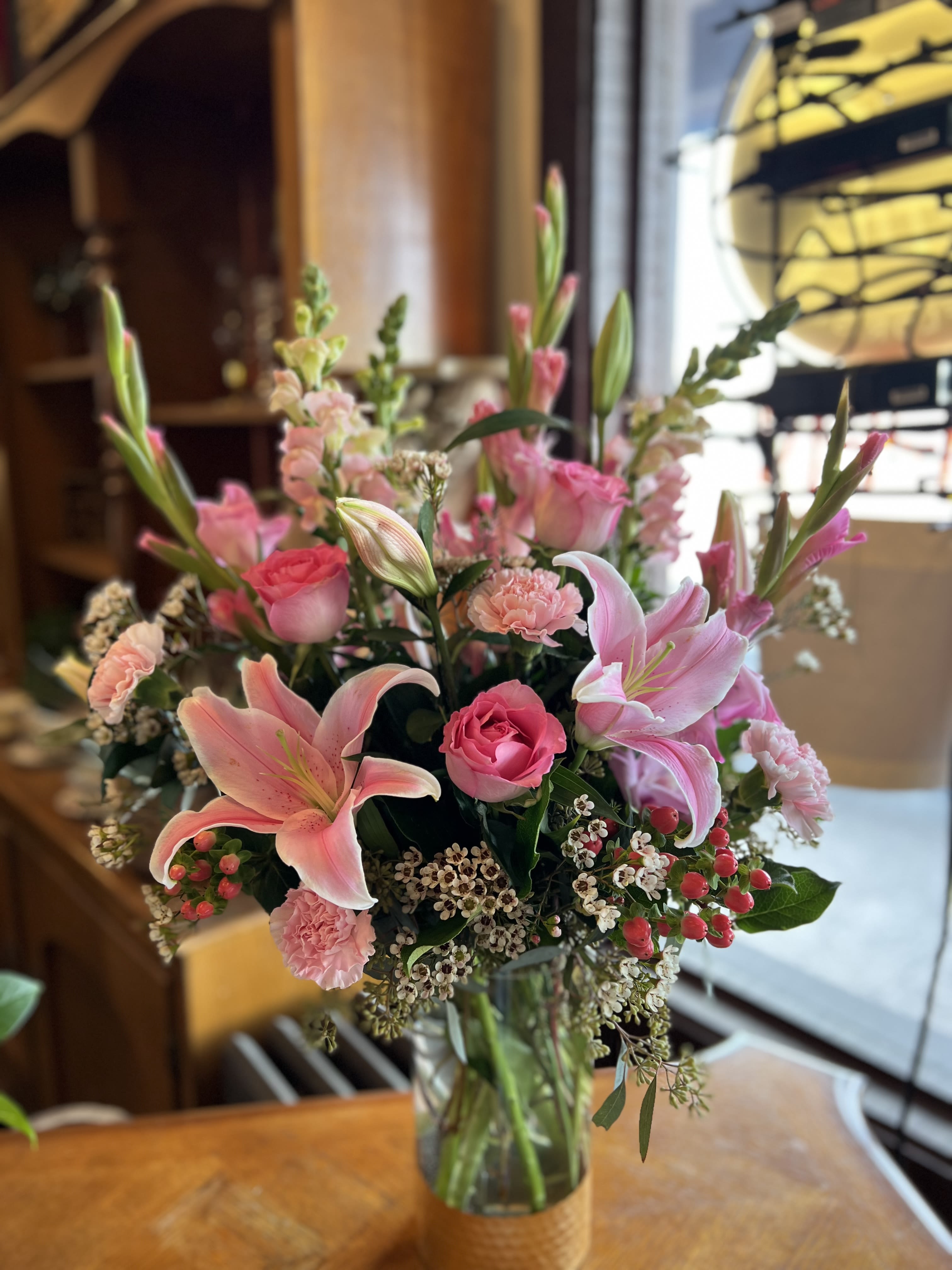 Phases of Love  - This all-pink grand arrangement is a showstopper, designed to captivate with its stunning variety and elegant charm. Standing tall in a gold-rimmed vase, the arrangement contains gladiolus, stargazers, snap dragons, carnations, roses, hypericum berries, and an assortment of greenery. Together, these elements form a breathtaking display that radiates love, beauty, and elegance—perfect for any grand celebration of romance.