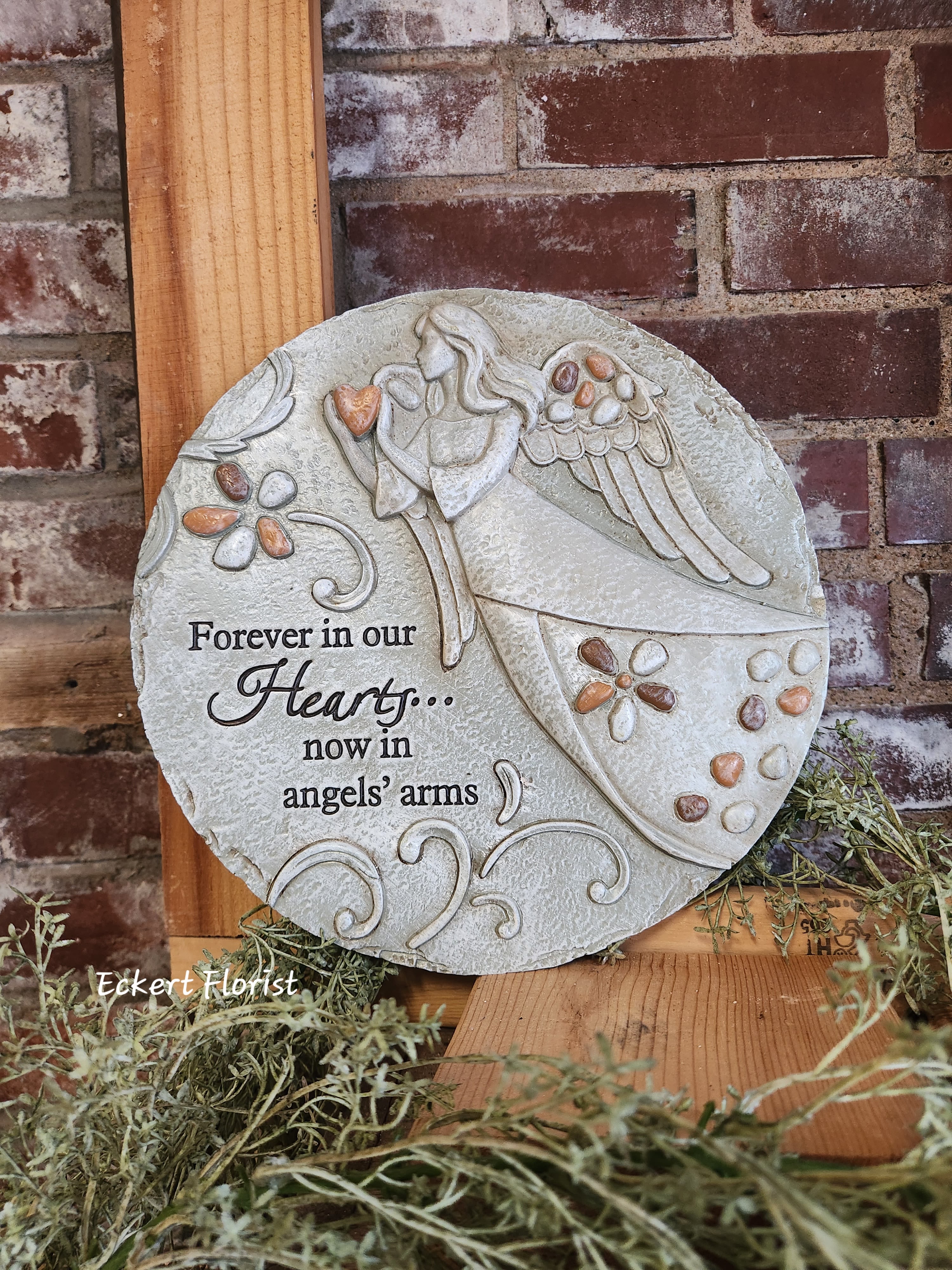 Eckert Florist's &quot;Forever In Our Hearts...&quot; Round Memorial Stone *Ou Local delivery Only - Round resin stone measures approx. 10.5&quot; Diameter  This nice memorial keepsake may be sent to a funeral/memorial service or home. Can be added to a green plant or fresh arrangement. See Deluxe or Premium upgrades. Sentiment: &quot;Forever in our hearts....Now in angles arms&quot; *See Add-on Section for Display Easel *LOCAL DELIVERY ONLY