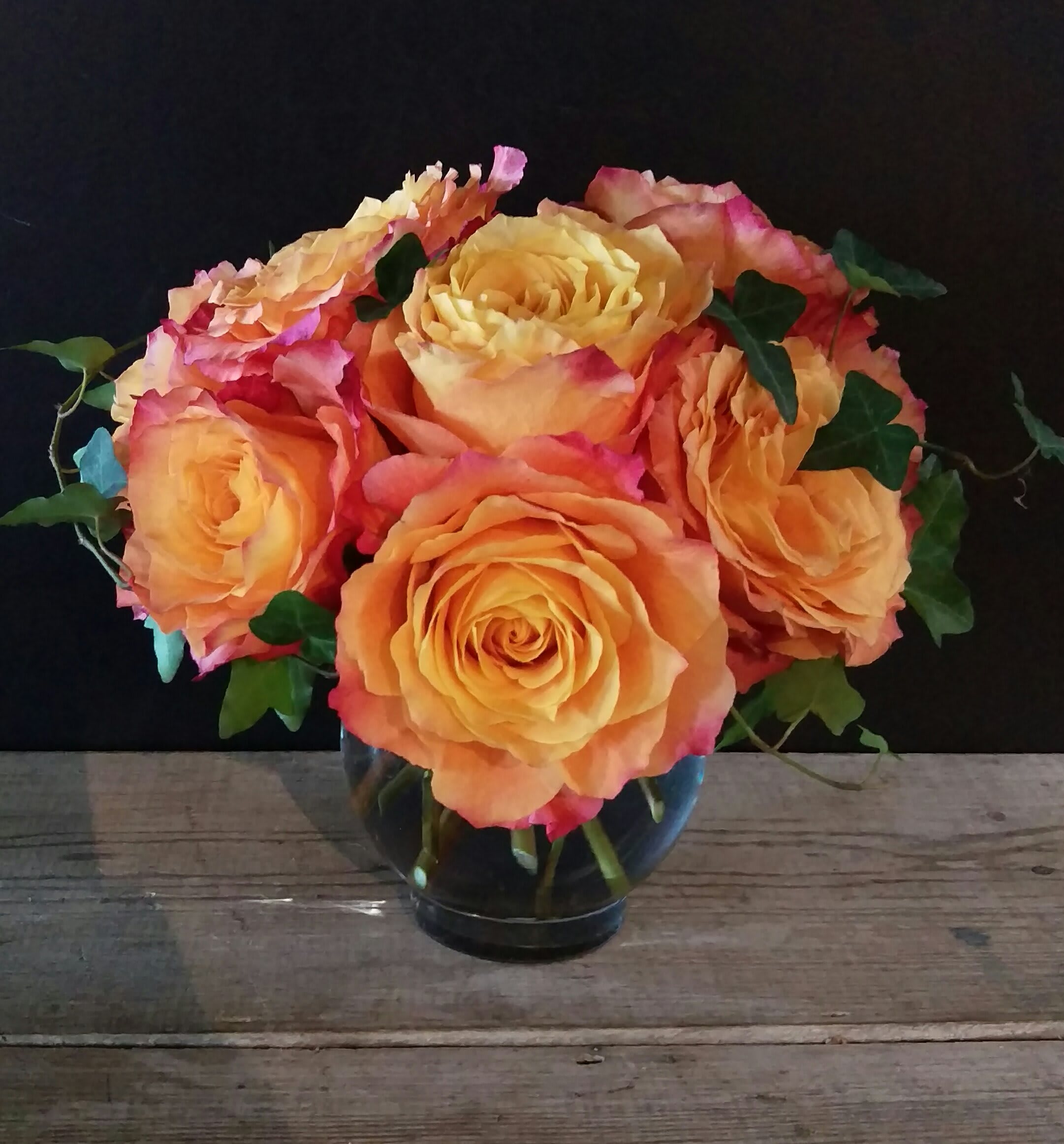 Tennessee Sunset Tennessee Sunset - A gorgeous cluster of an amazing rose, Free Spirit. Considered a garden rose... this bloom has all the colors of a Tennessee Sunset in summer. Coral, orange, yellows and a hint of pink.. .accented with just a touch of ivy. Brighten a room.. spark a soul... perfect floral gift to bring a gleam to any eye. Approx 10" x 10"