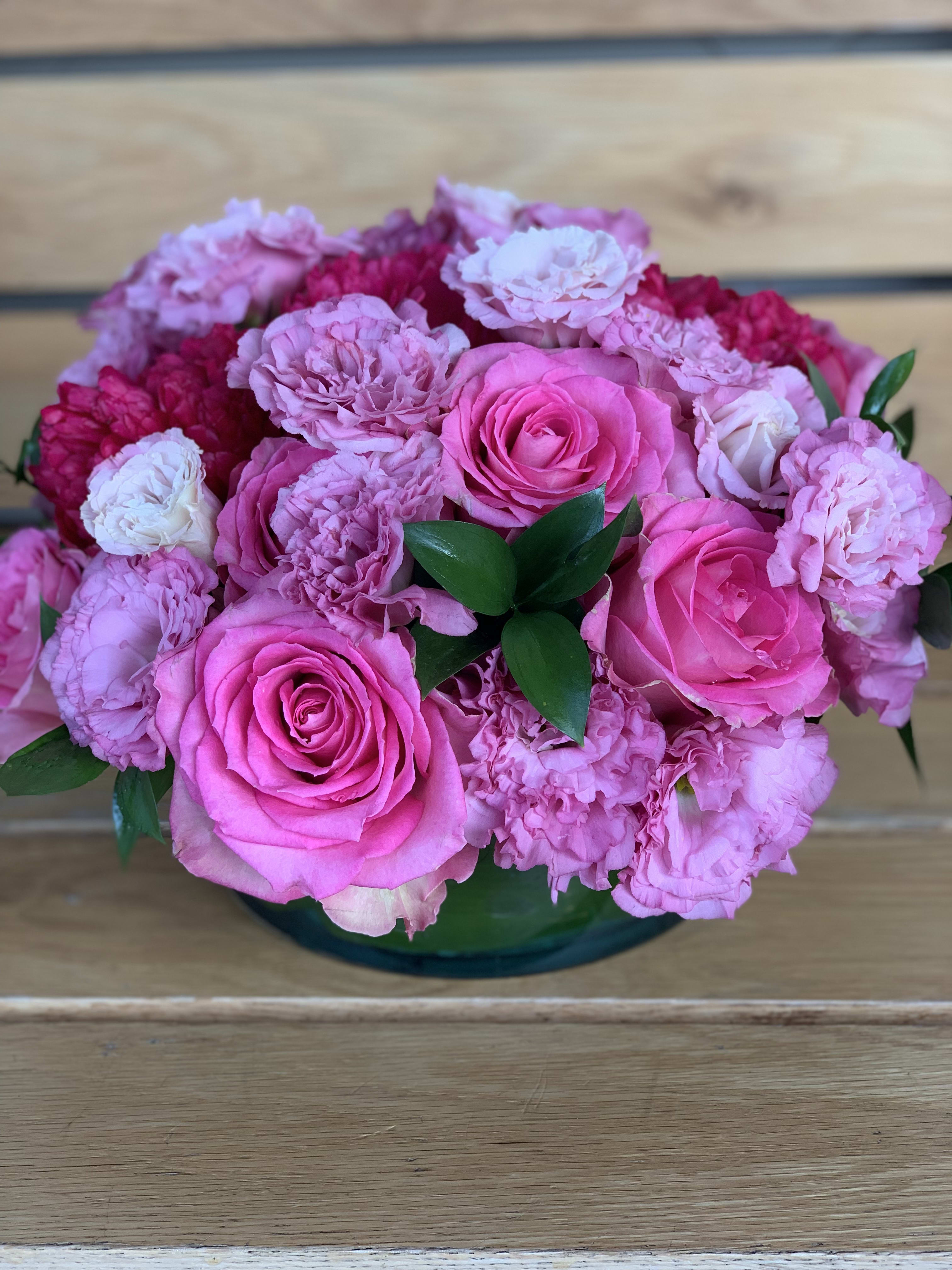 Dolores Centerpiece  - A low round vase filled with pink roses, lisianthus, hyacinths and touch of green. 