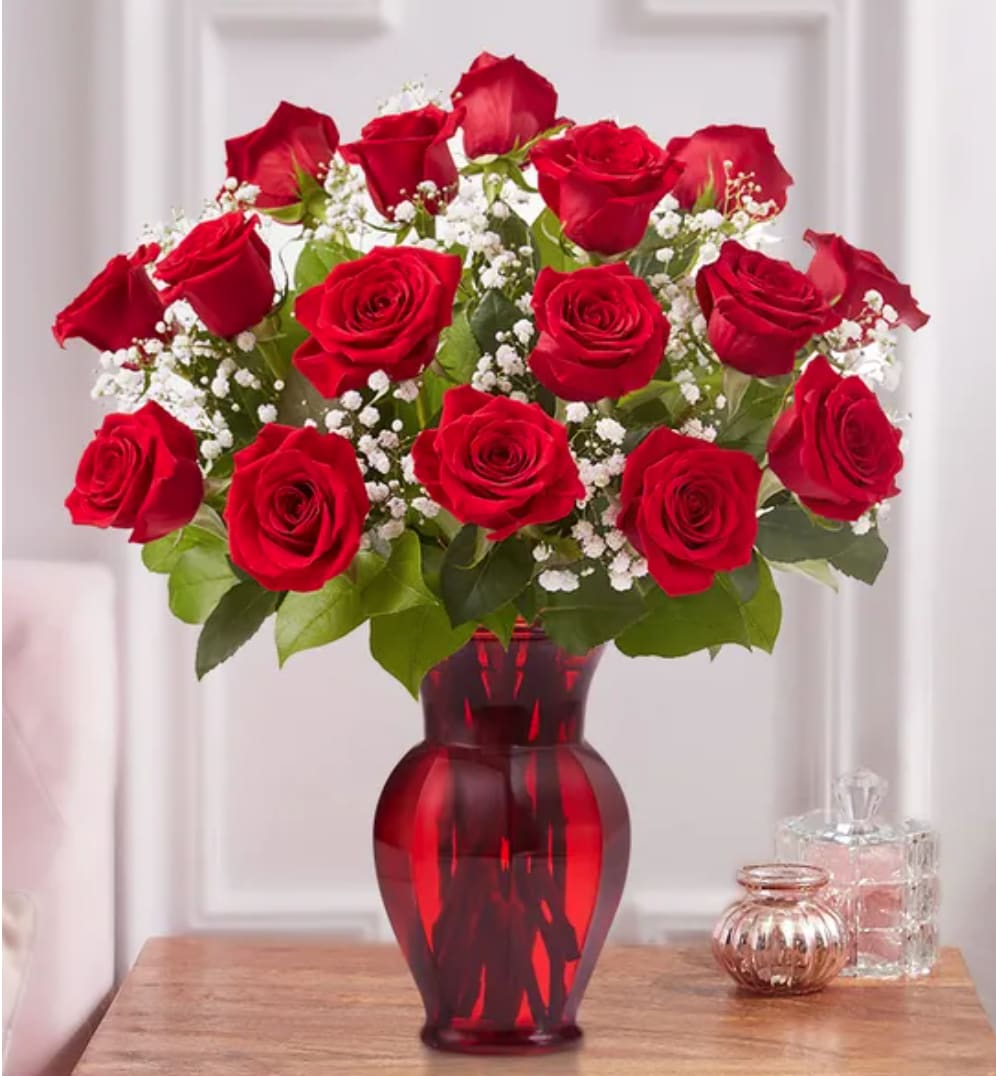 Blooming Love - Sometimes flowers speak louder than words…and our elegant red roses speak volumes! Beautifully hand-arranged with lush greenery inside our exclusive ruby red vase, each radiant bloom will help you express your love in the most romantic way possible (18 roses)