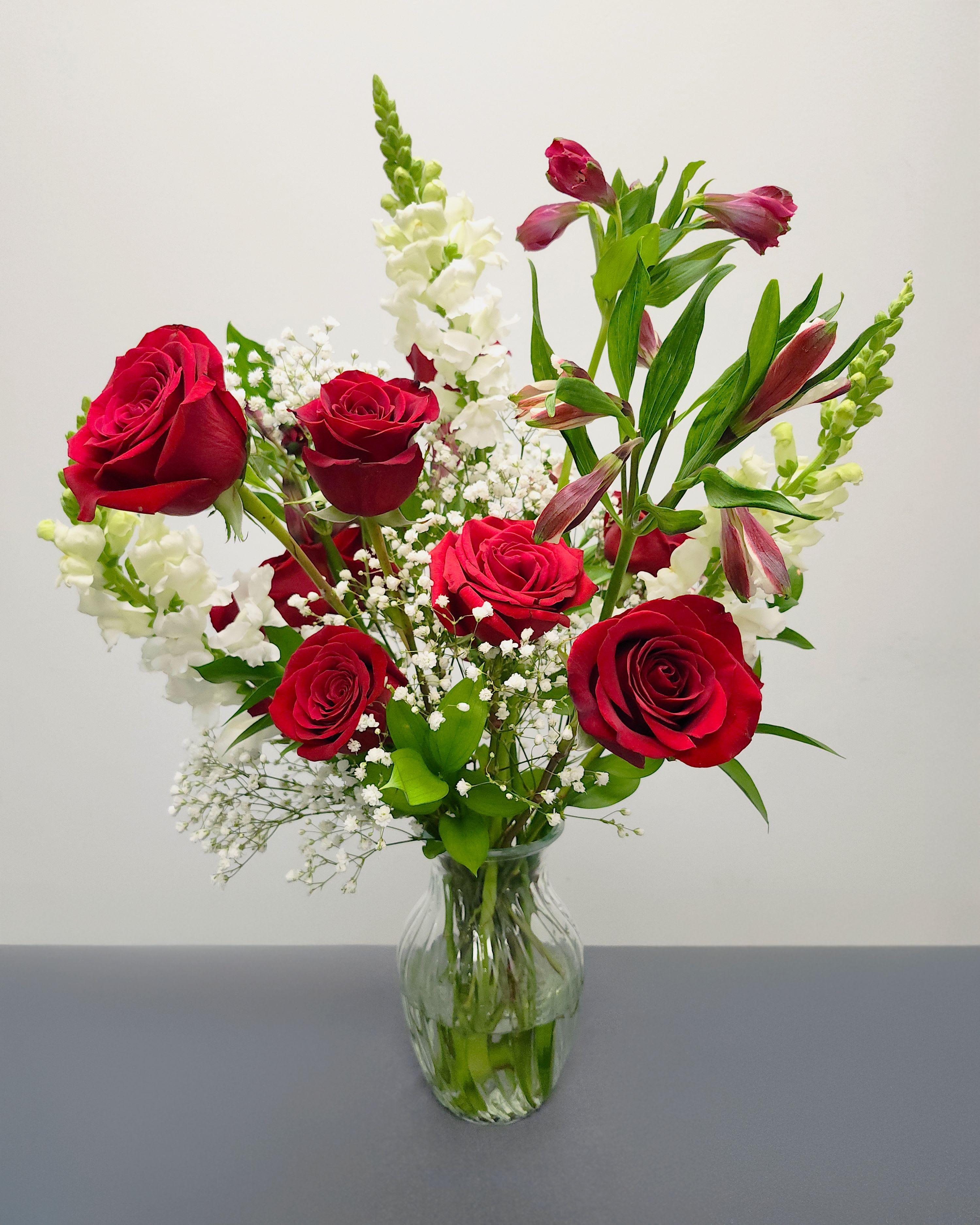 Roses are Red I luv U - Make a grand statement with 12 premium red roses, filled with lush greenery, snapdragons, and baby's breath. The ultimate classic Valentine's Day arrangement that she will love.