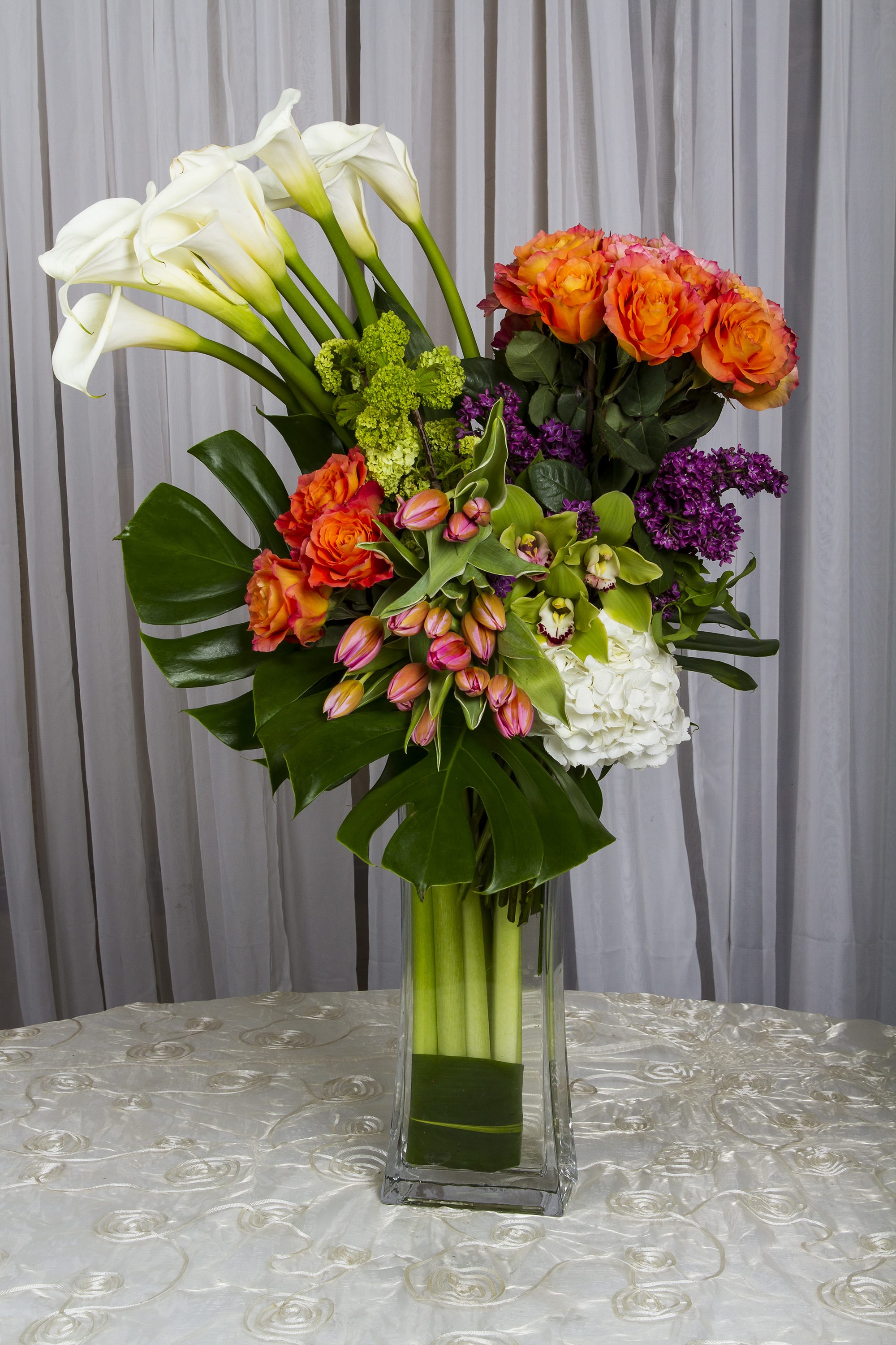 Tall and Modern Tall and Modern - Wow mom with this beautiful arrangement of roses, hydrangeas, lilacs, viburnum, tulips, calla lilies, and orchids in a tall modern glass vase.